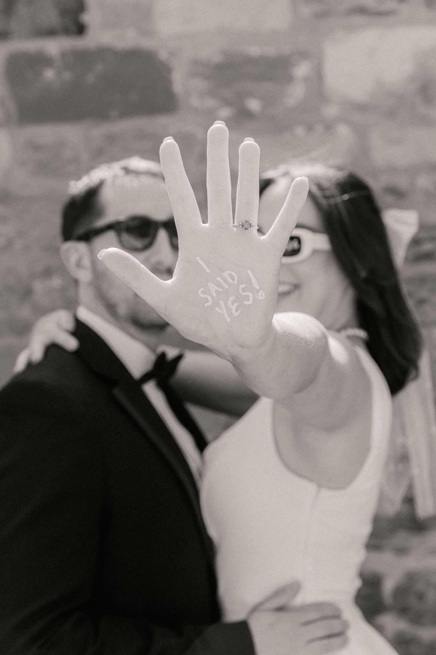 future bride and groom standing together with bride holding hand out that says 