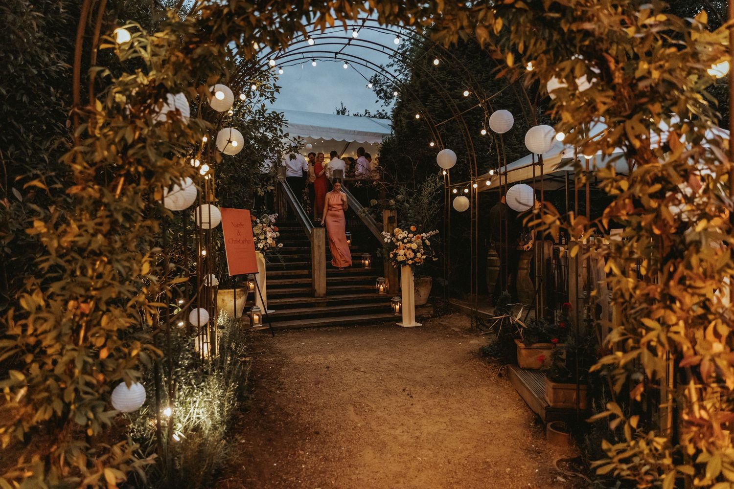 Ivy archway with lanterns leading to dance floor at wedding