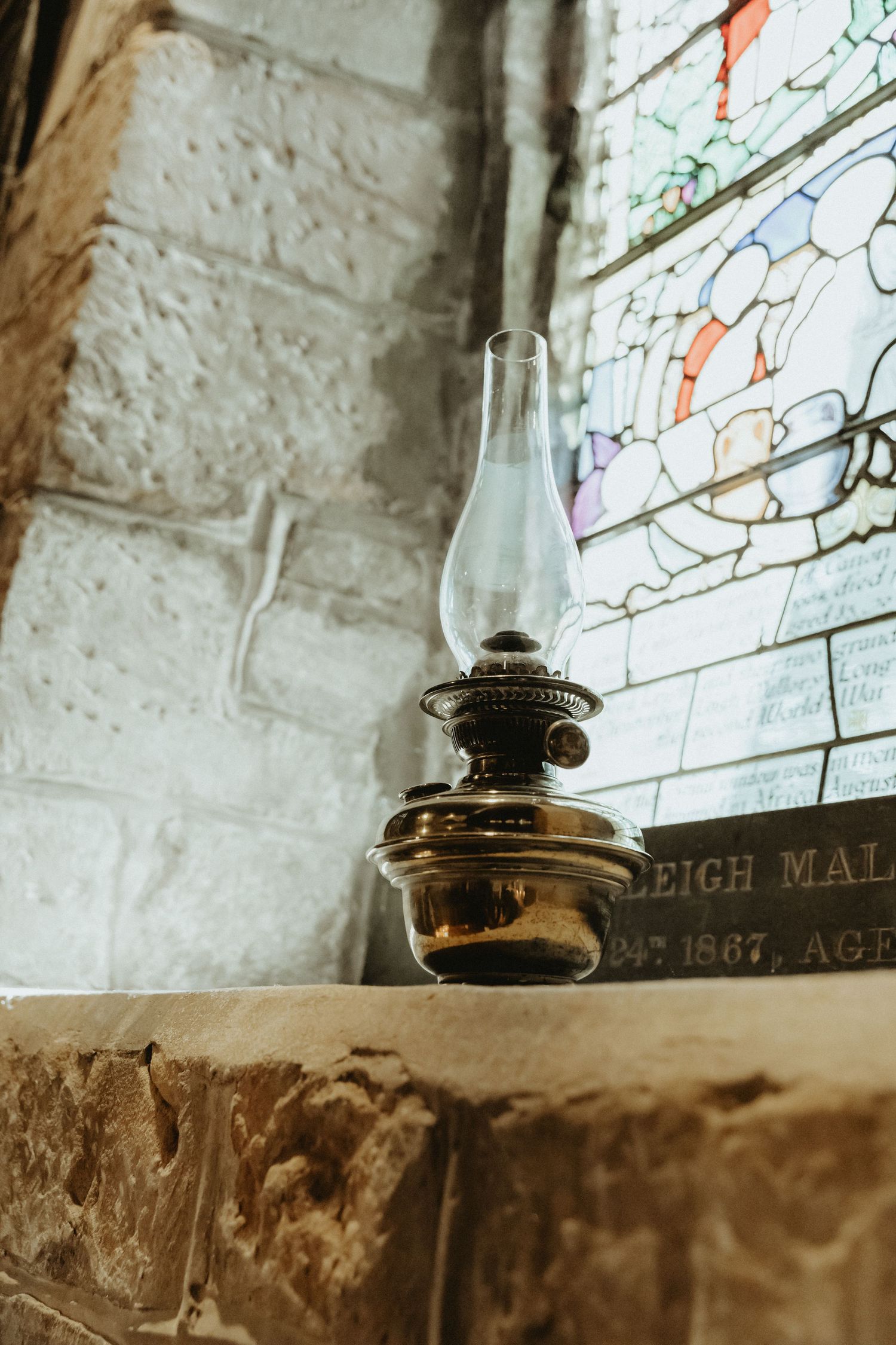Oil lamp on window sill at St Wilfrids church in Mobberley Cheshire with light coming through stain glass window