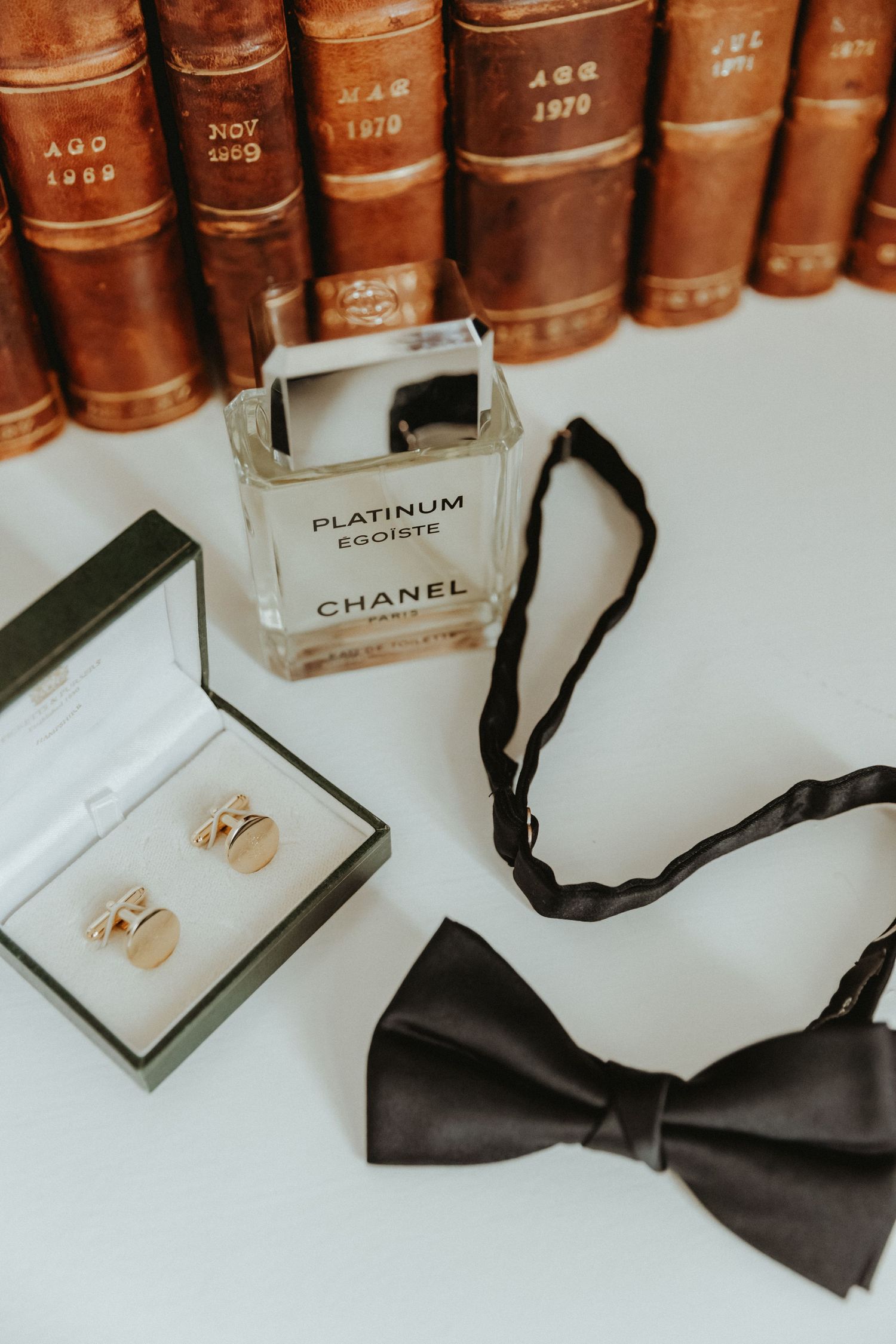 Grooms fragrance flat lay with cufflinks and bow tie during groom prep at an airbnb