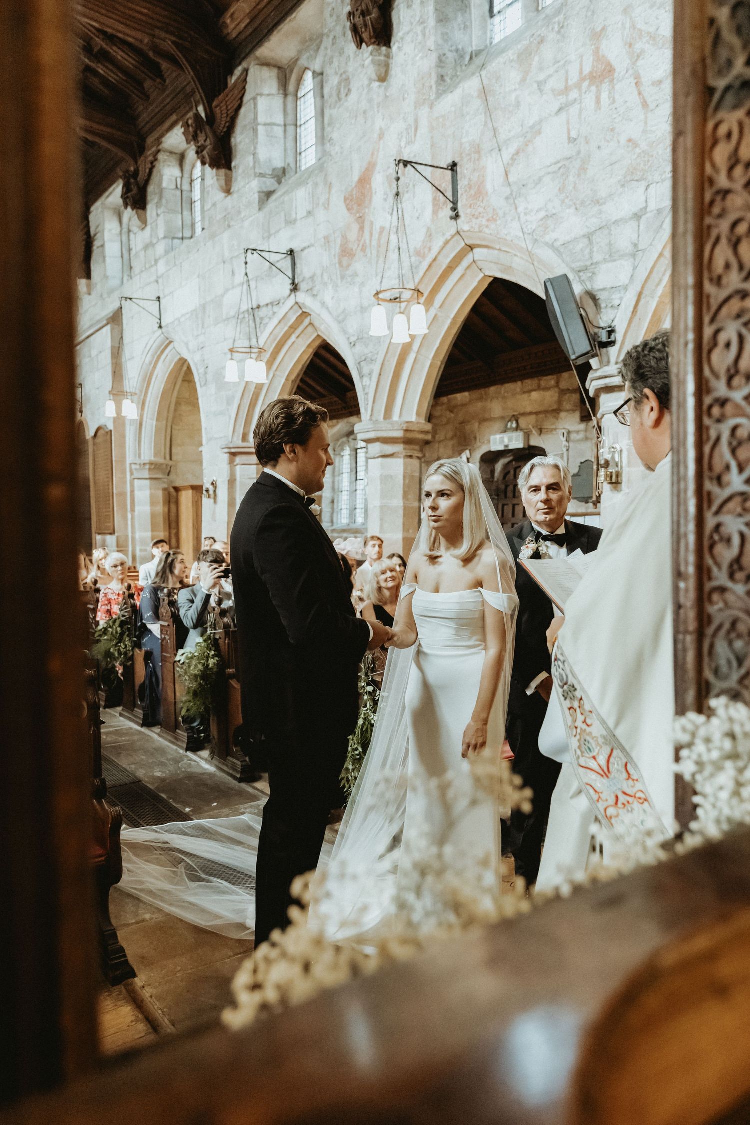 Bride and groom standing together at top os aisle at St Wilfrids church in Mobberley