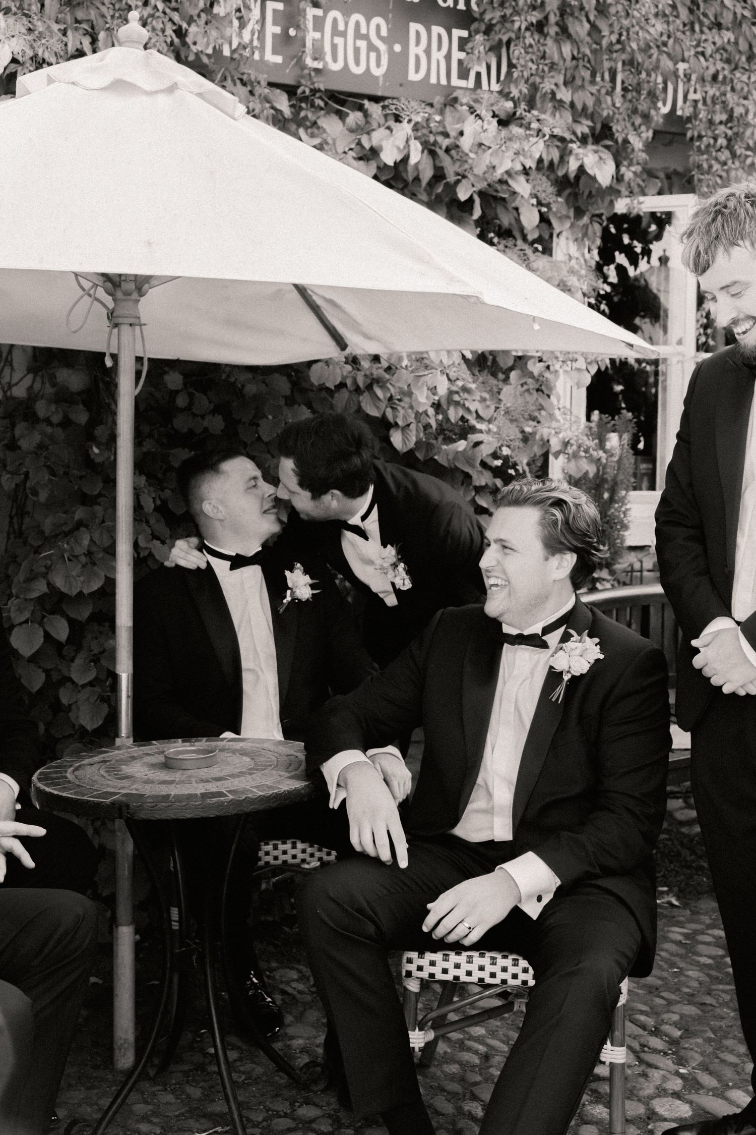 Groom laughing with groomsmen during group portraits on wedding at Roebuck Inn