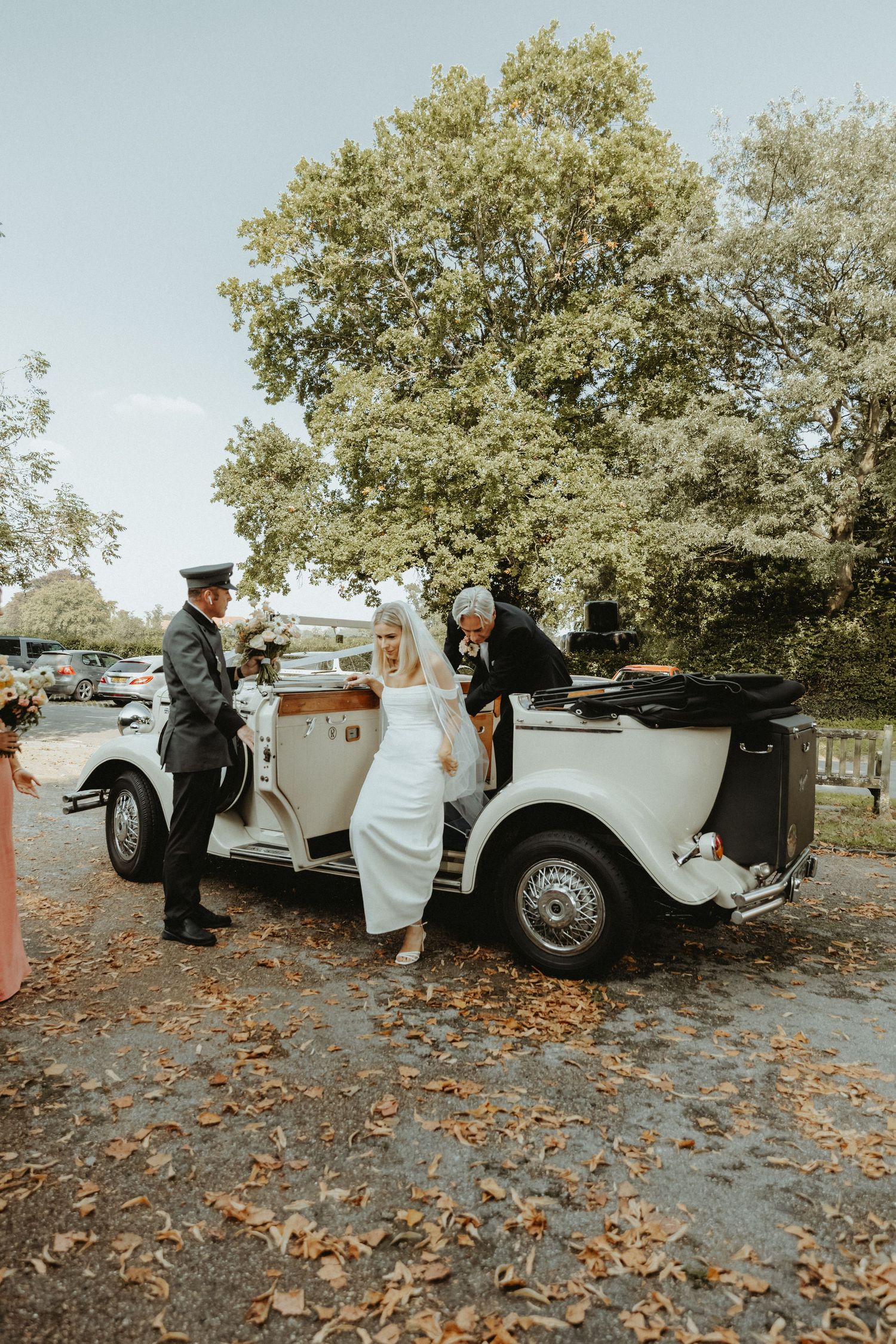 Bride getting out of vintage wedding car outside church in Cheshire