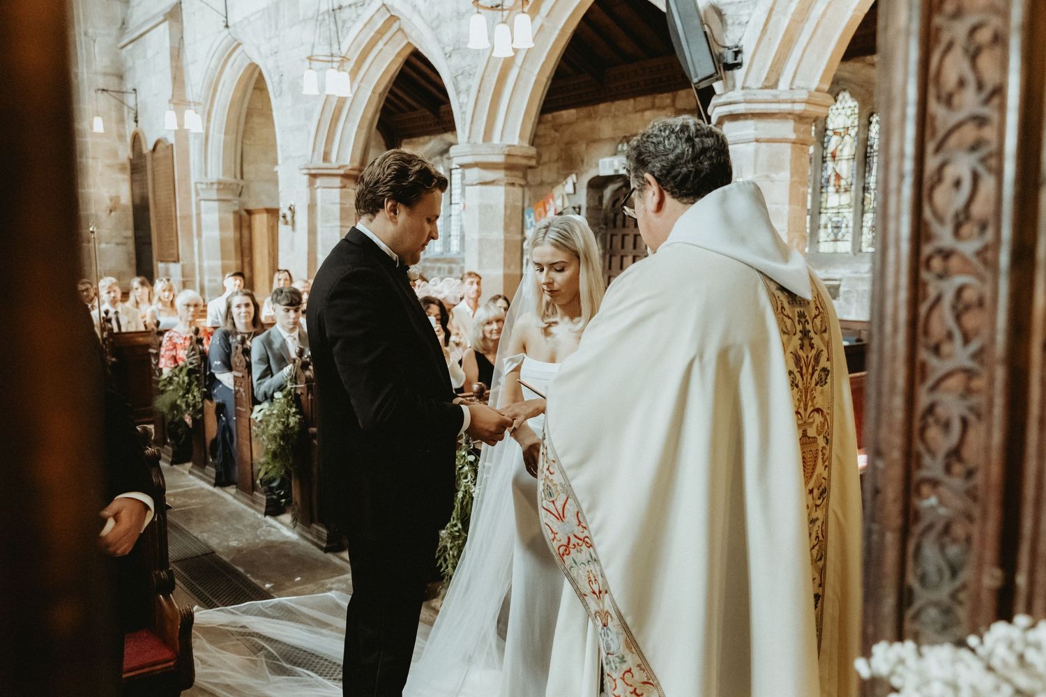 Priest standing with bride and groom at top of church performing their catholic ceremony