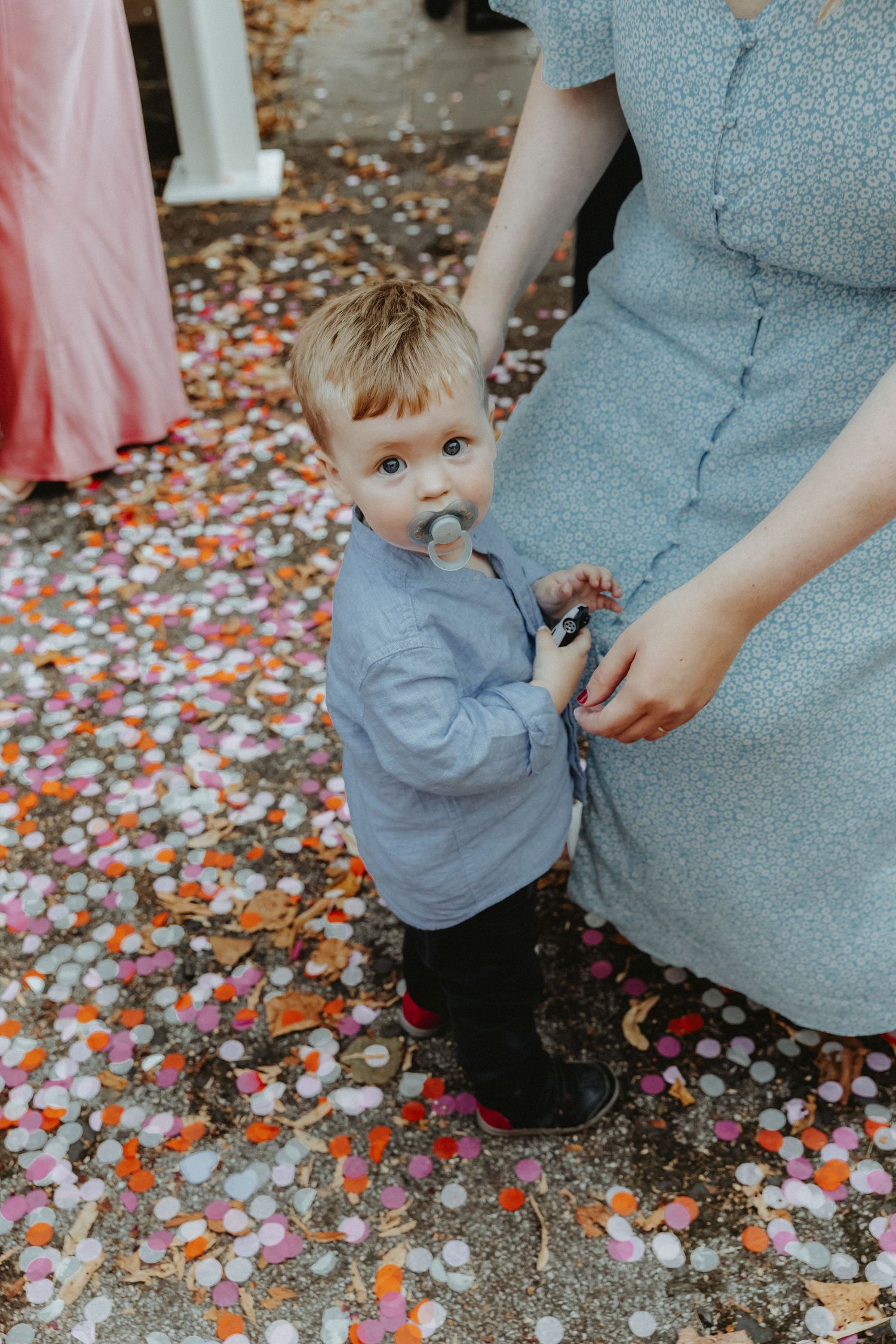 Small child with his mum looking up at camera after playing in the recently thrown confetti
