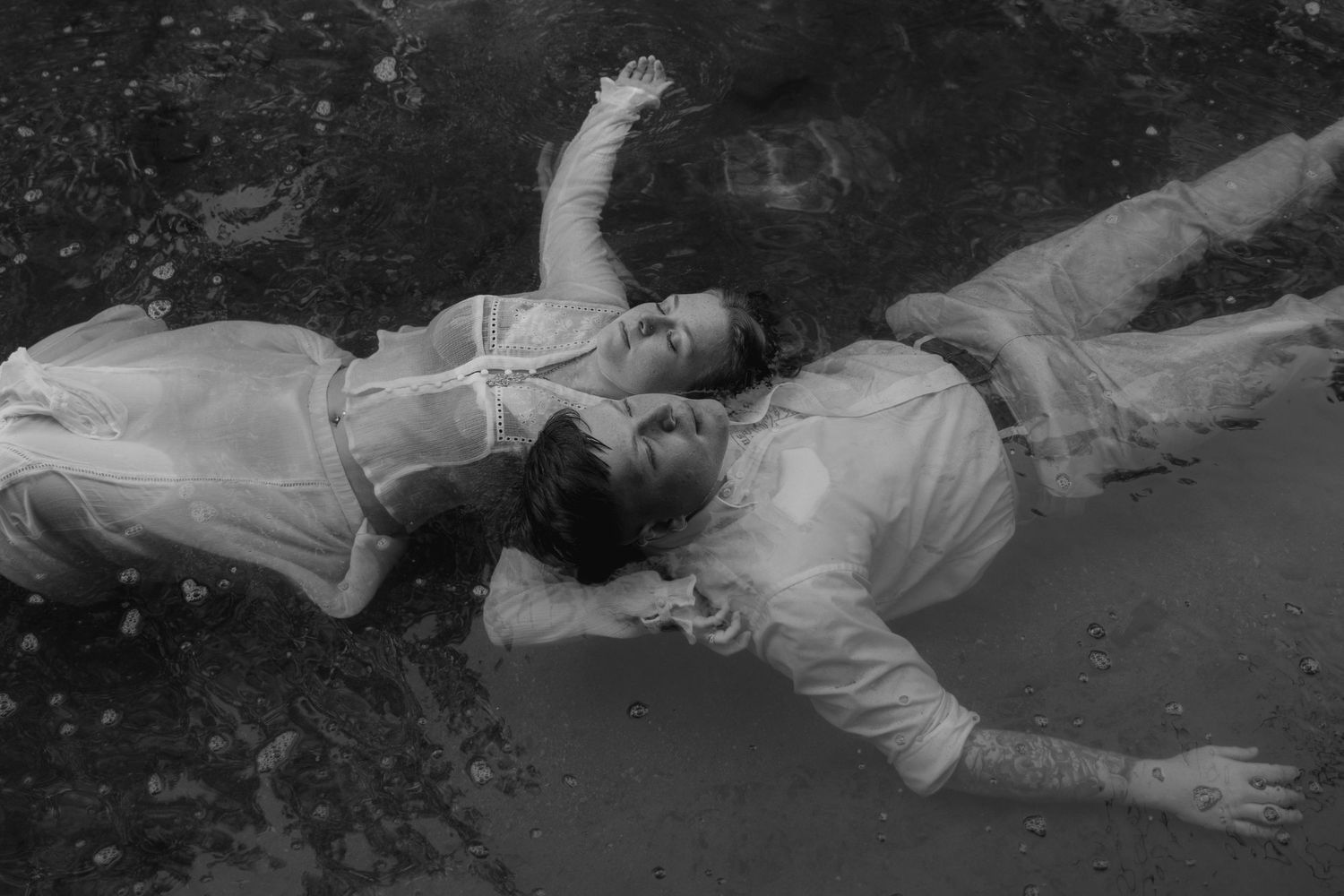 Boy and girl floating in water fully engulfed in their thoughts and shutting out the world.