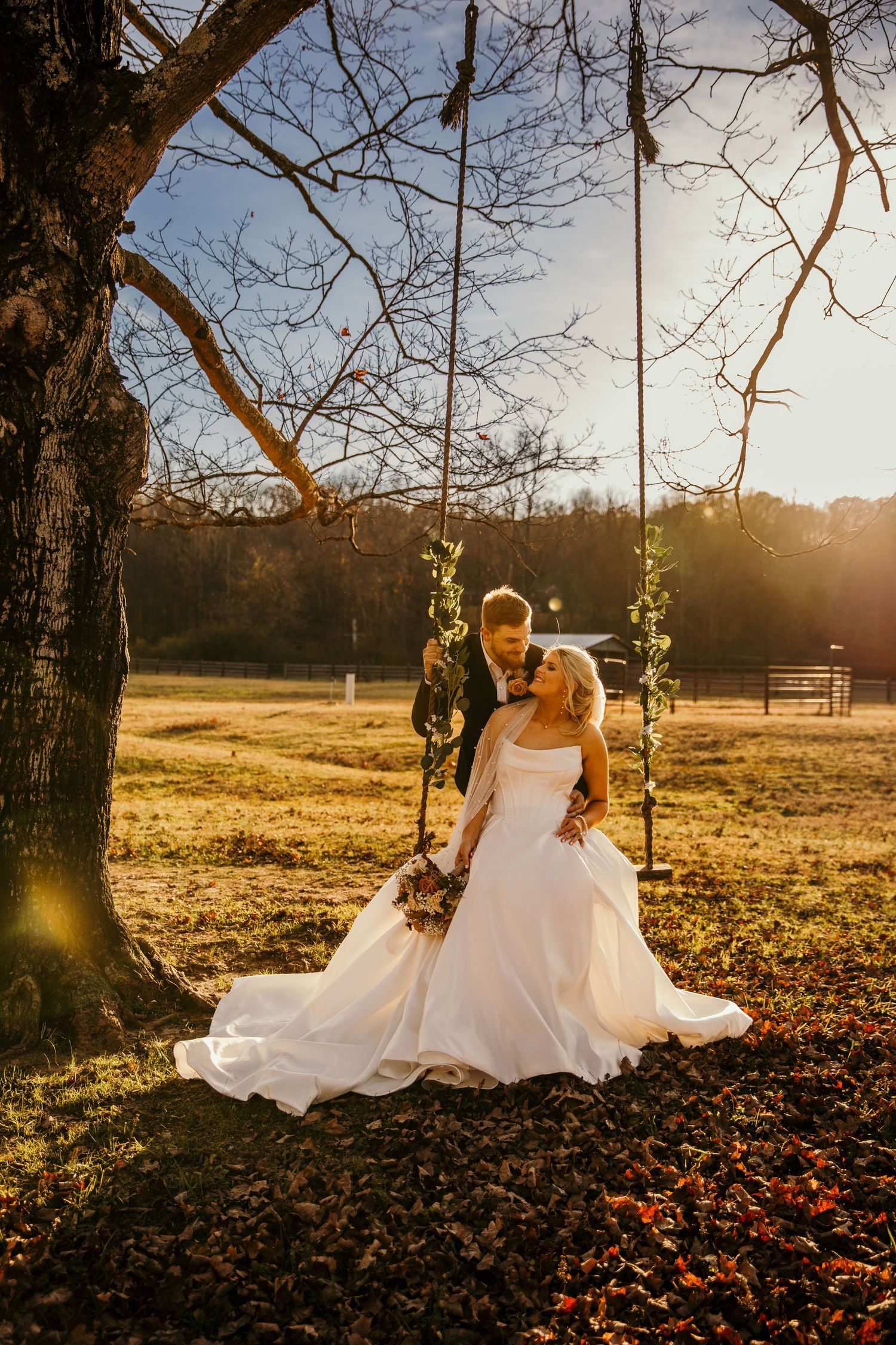 bride and groom sitting on a tree rope swing
