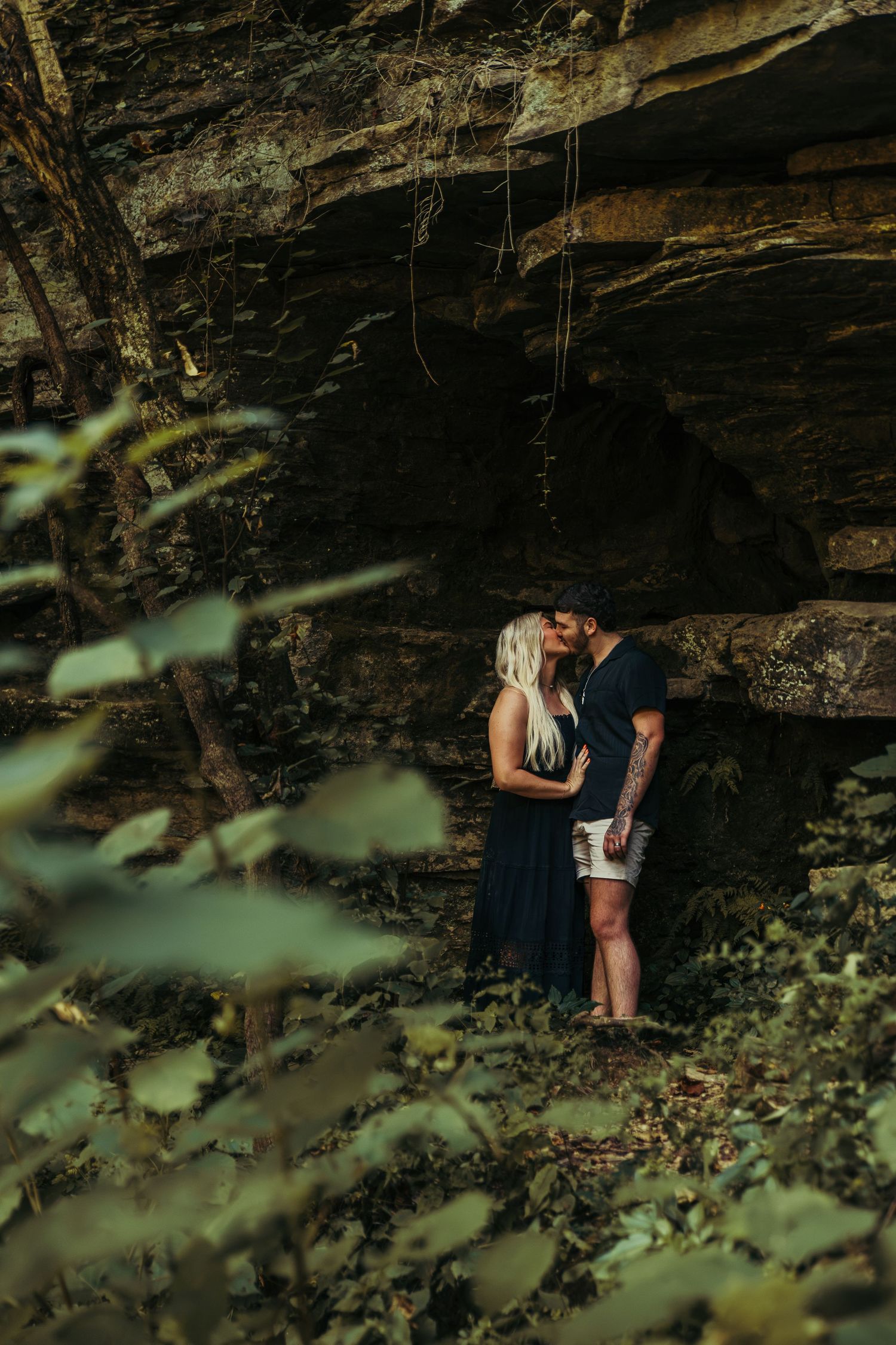 guy and girl leaned in close in front of a cave