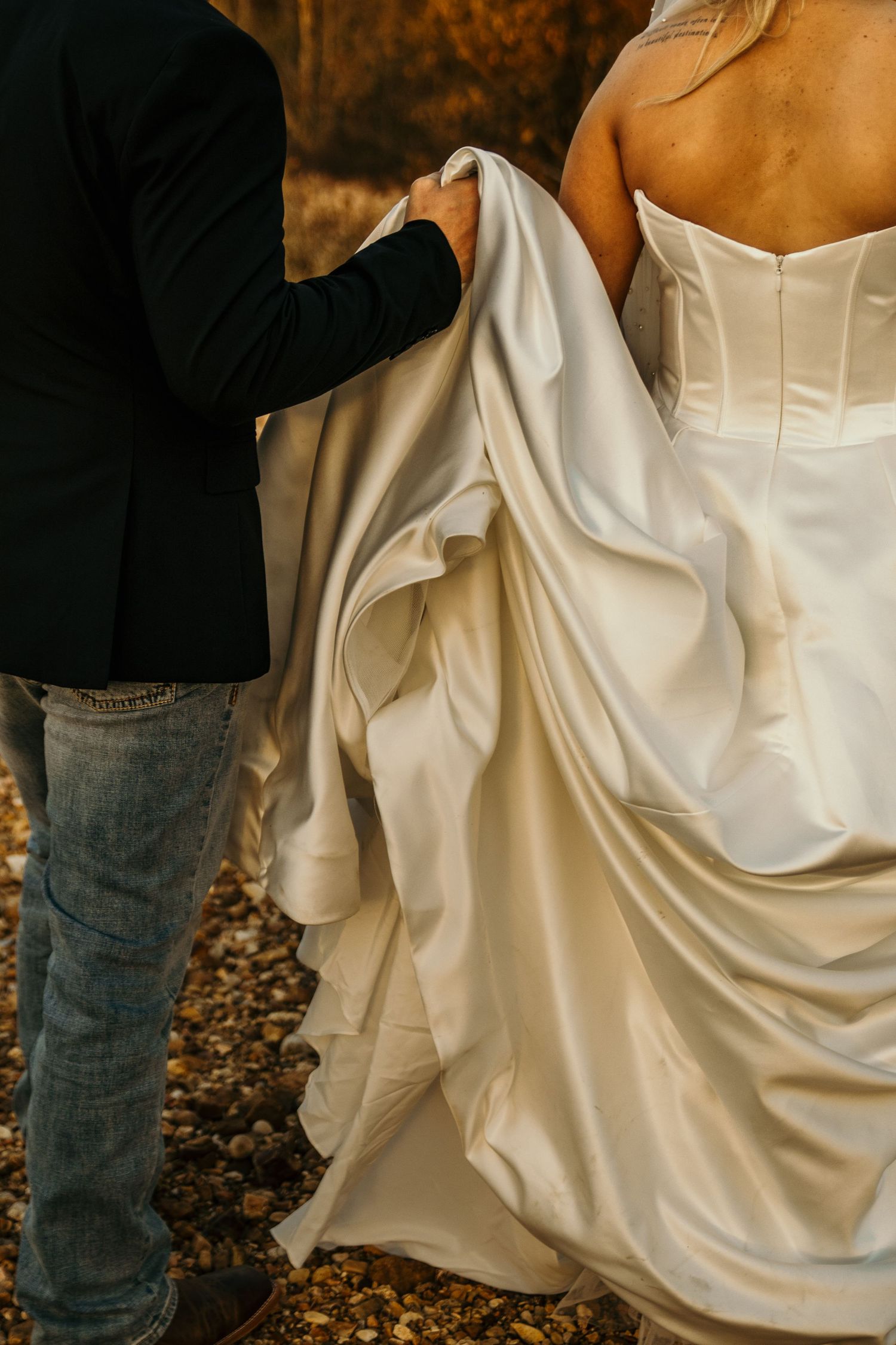 groom holding brides dress while walking