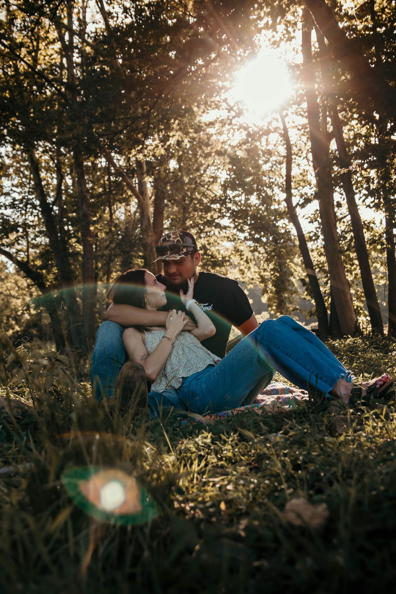 Boy and girl nestled under a tree reminiscing about their life together and what their future will be while the sunlight shines on them.
