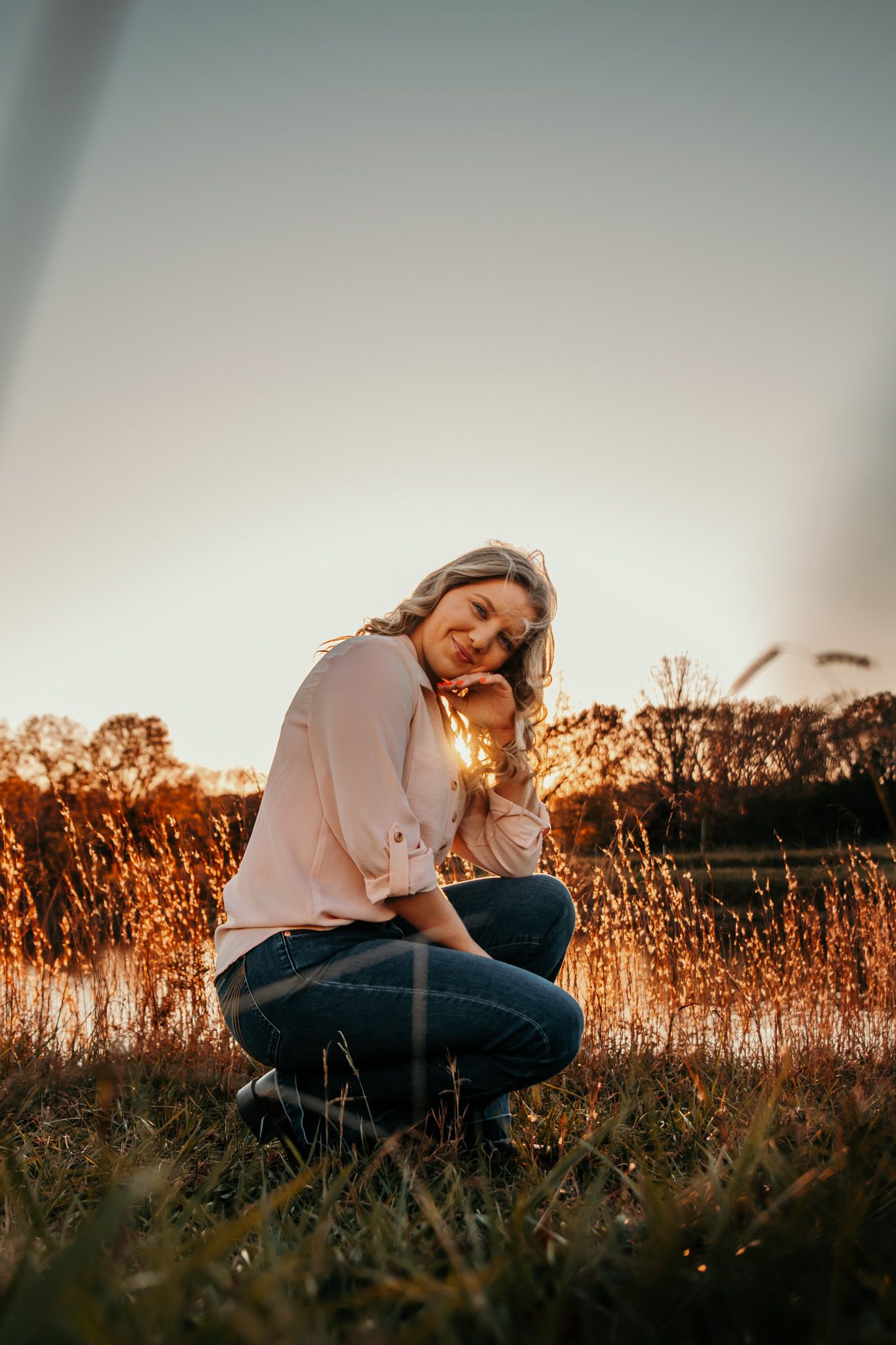 girl sitting in front of pond at golden hour