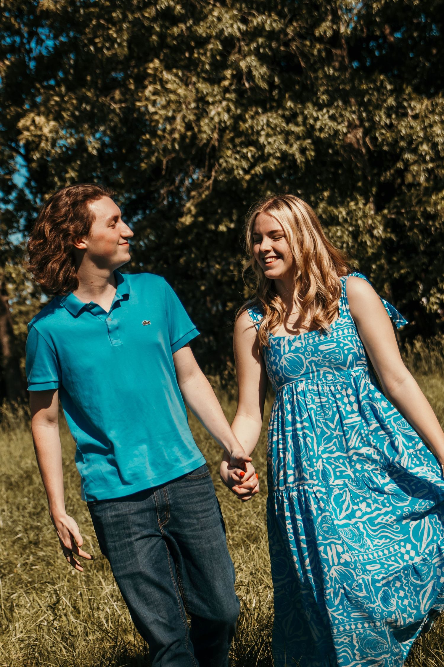 Boy and girl walking through a sunlit field holding hands and dreaming about life and enjoying the moment together.