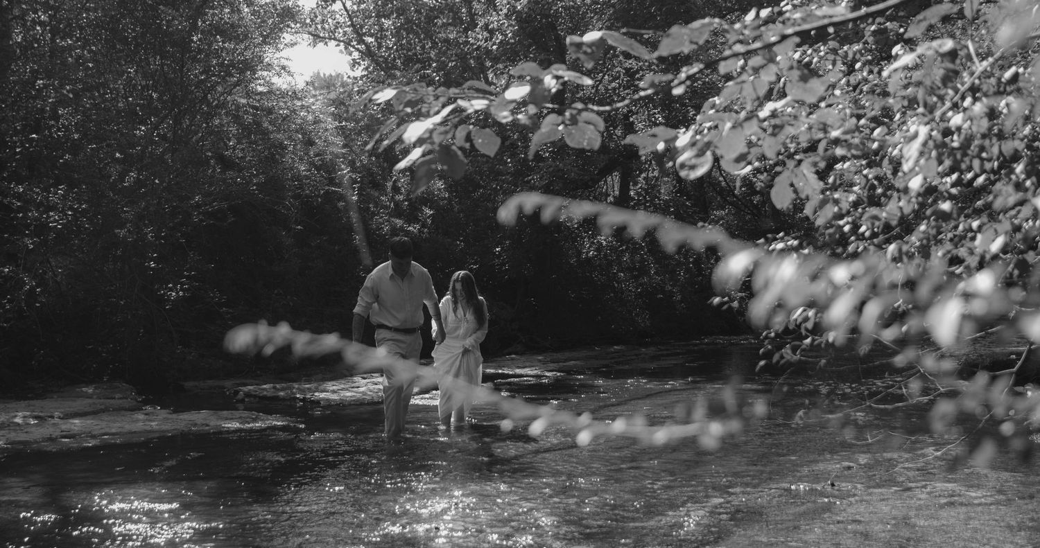 Boy and girl wading through the creek while laughing and trying to keep their balance.