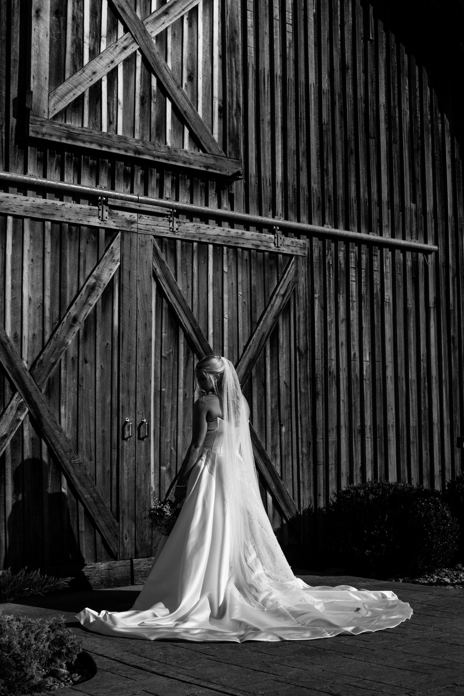 bridal portrait of the back of brides dress in front of rustic barn
