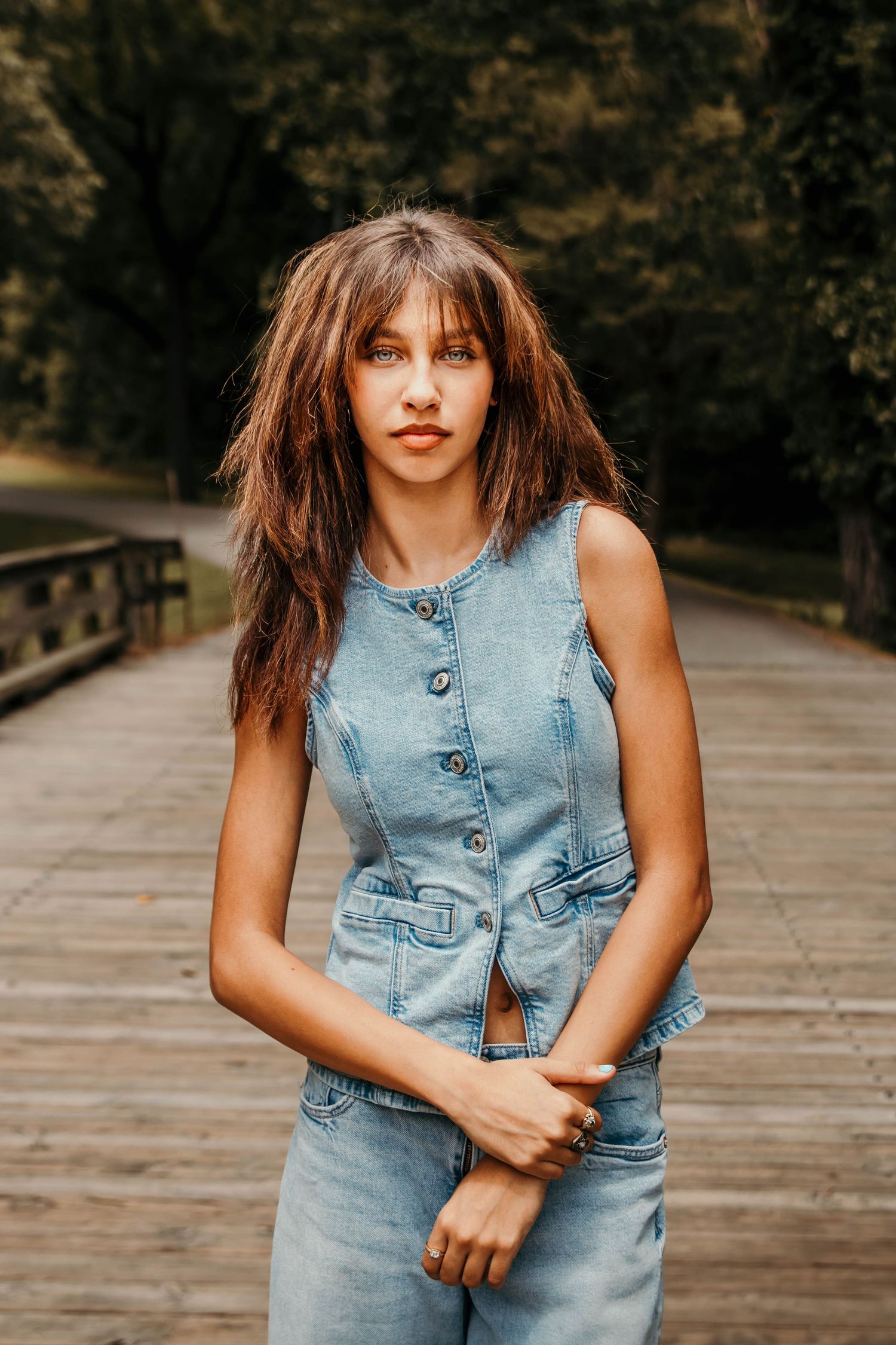 Girl crossing her arms while standing over an old drive over wooden bridge.