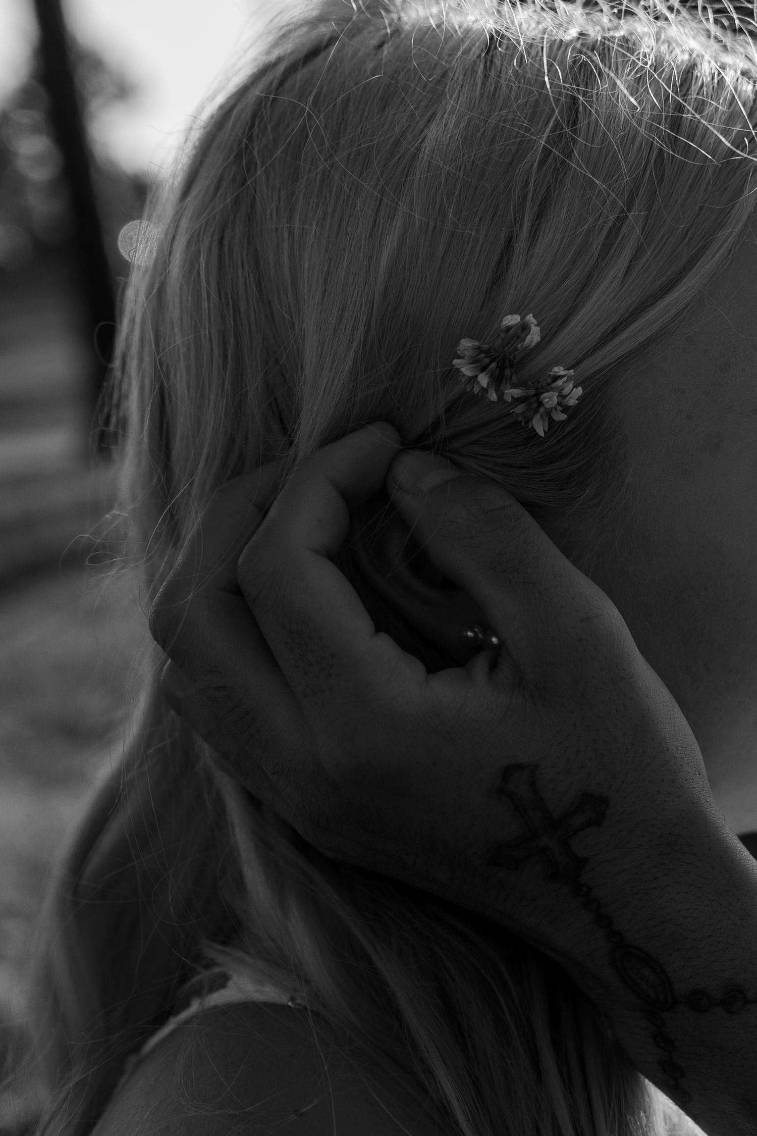guy pushing back hair and tucking in a flower behind a girls ear