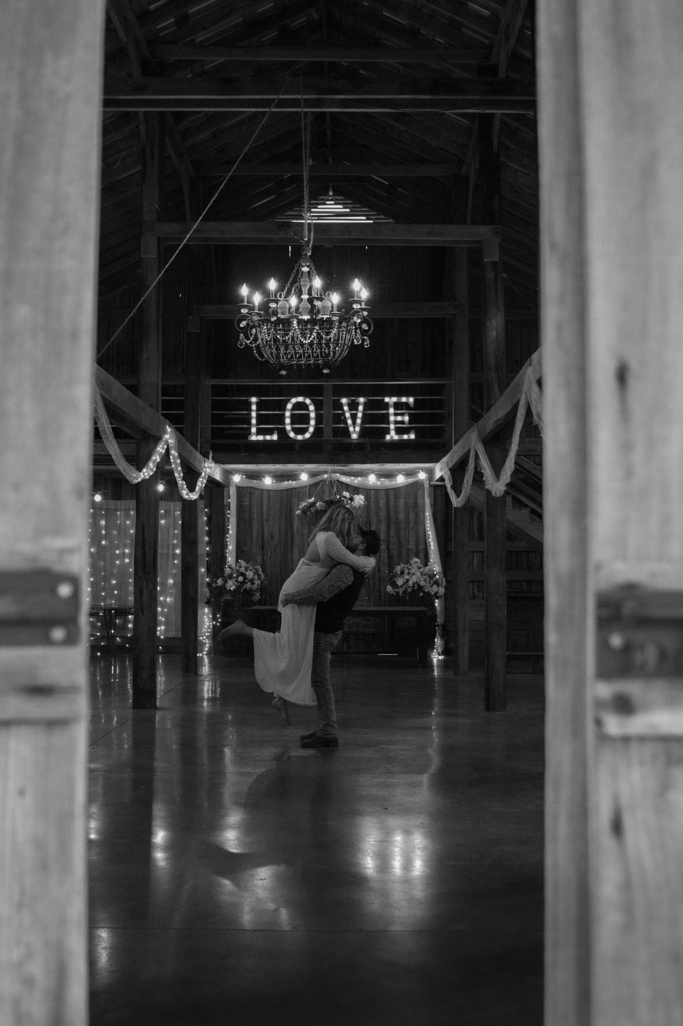 girl being picked up by boy in a rustic barn for engagement pictures