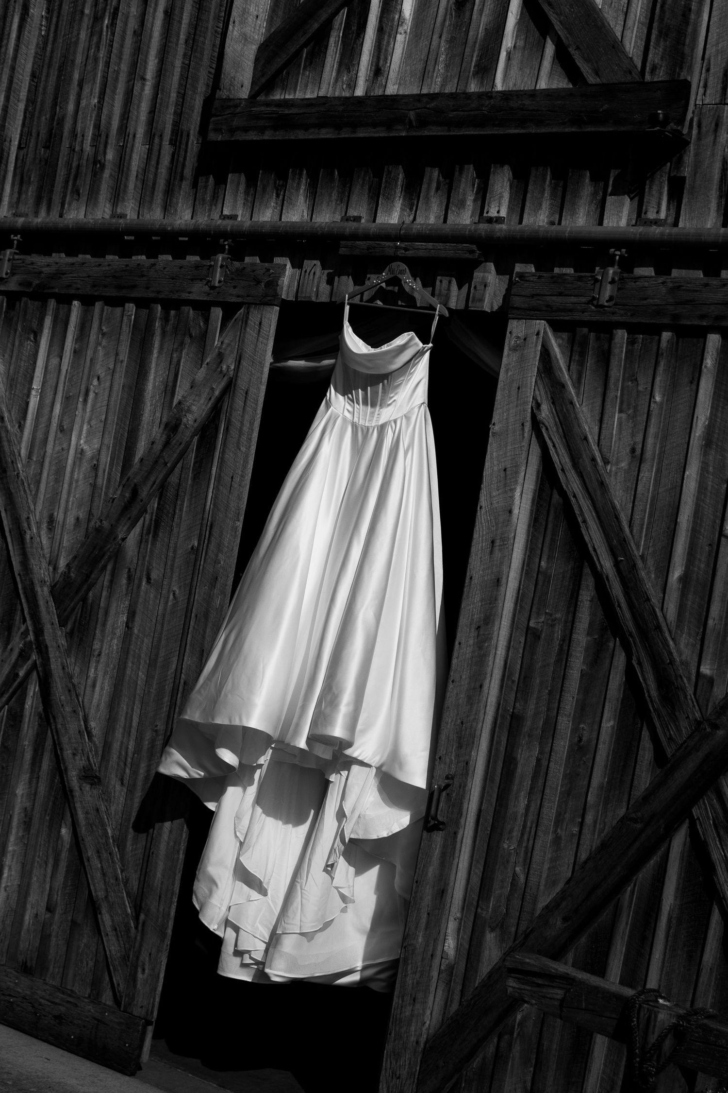 brides dress detail shot hanging from barn doors