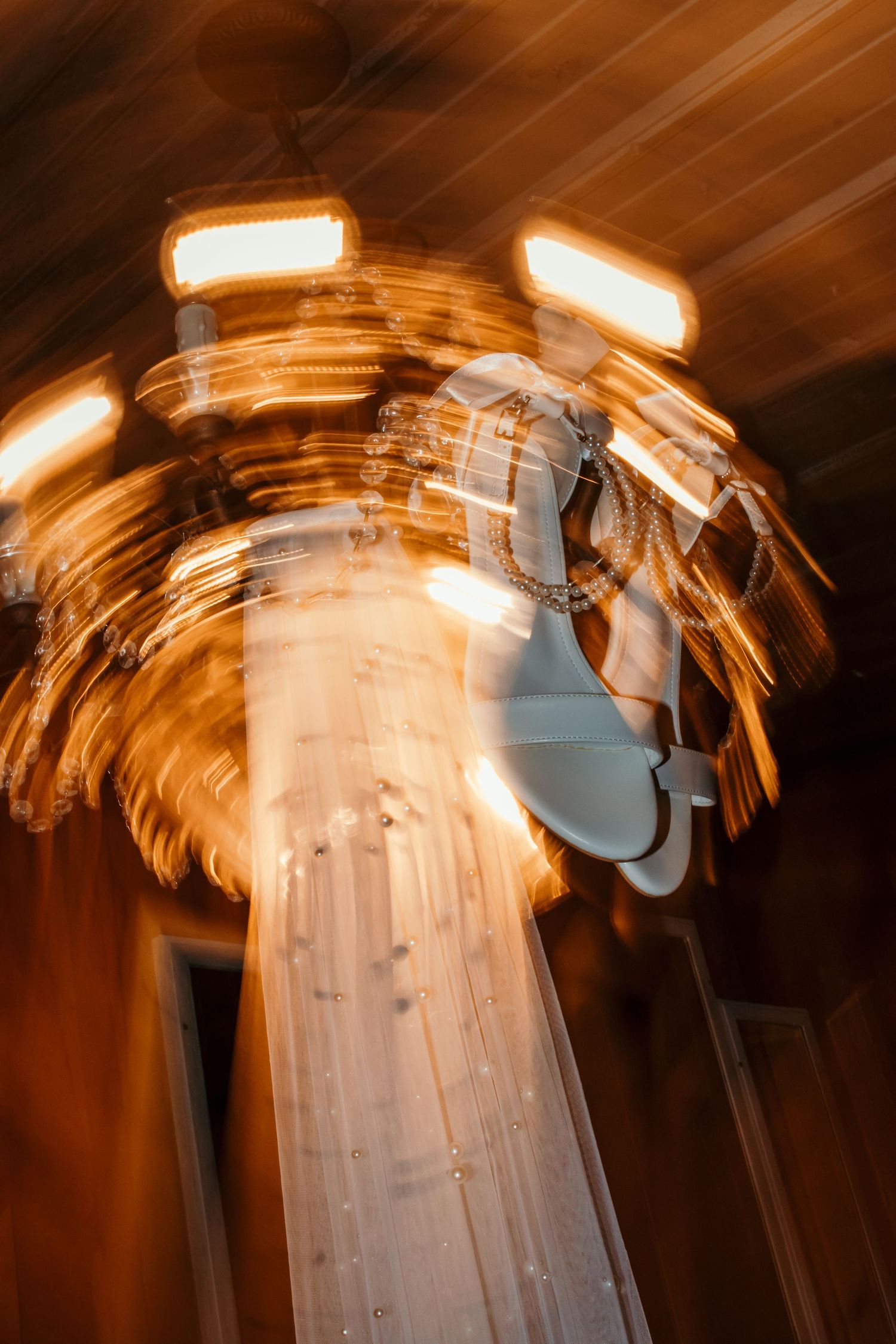 detail picture of brides heels and veil hanging from chandelier