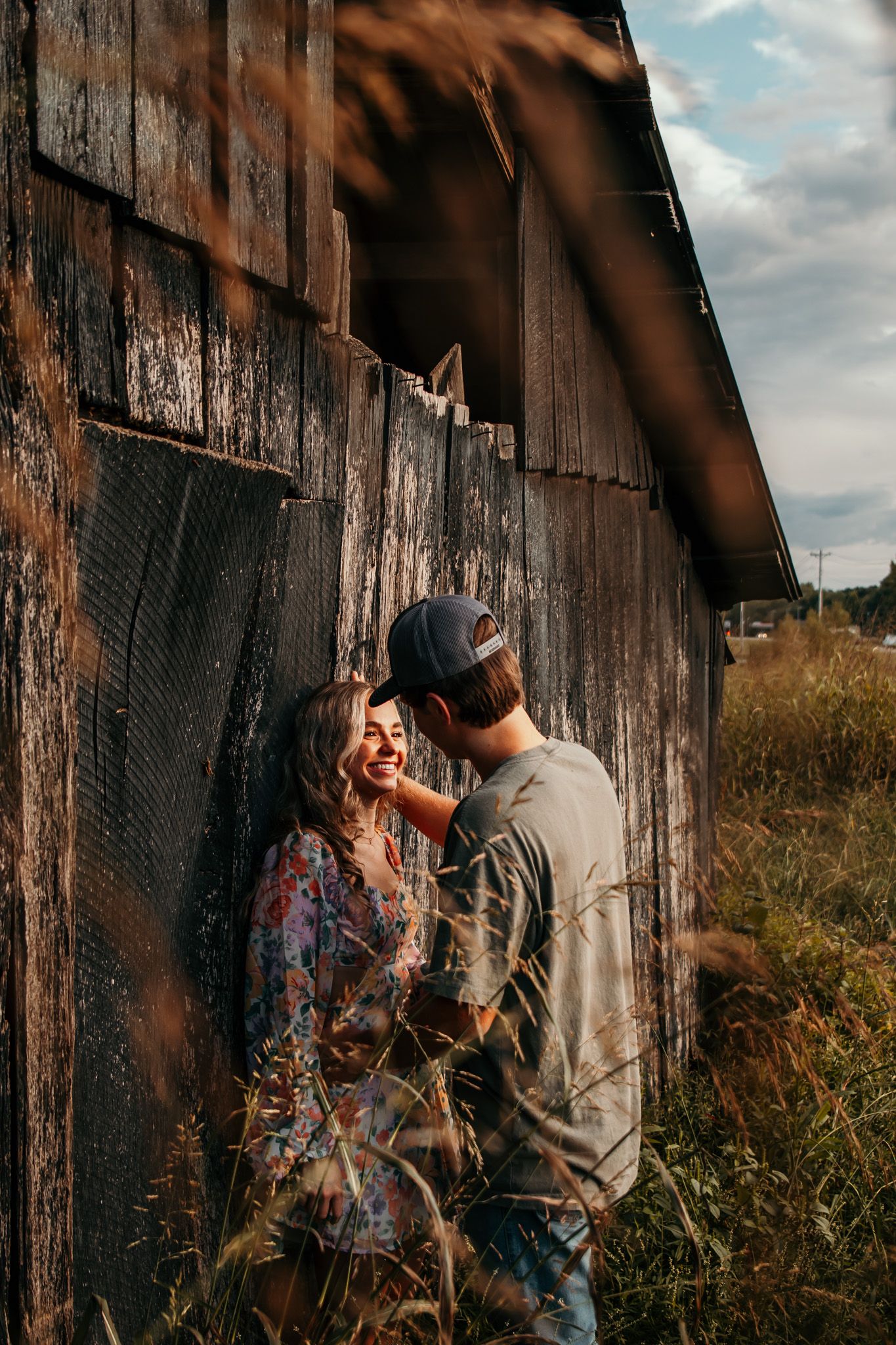 boy and girl against old barn gazing into each others eyes