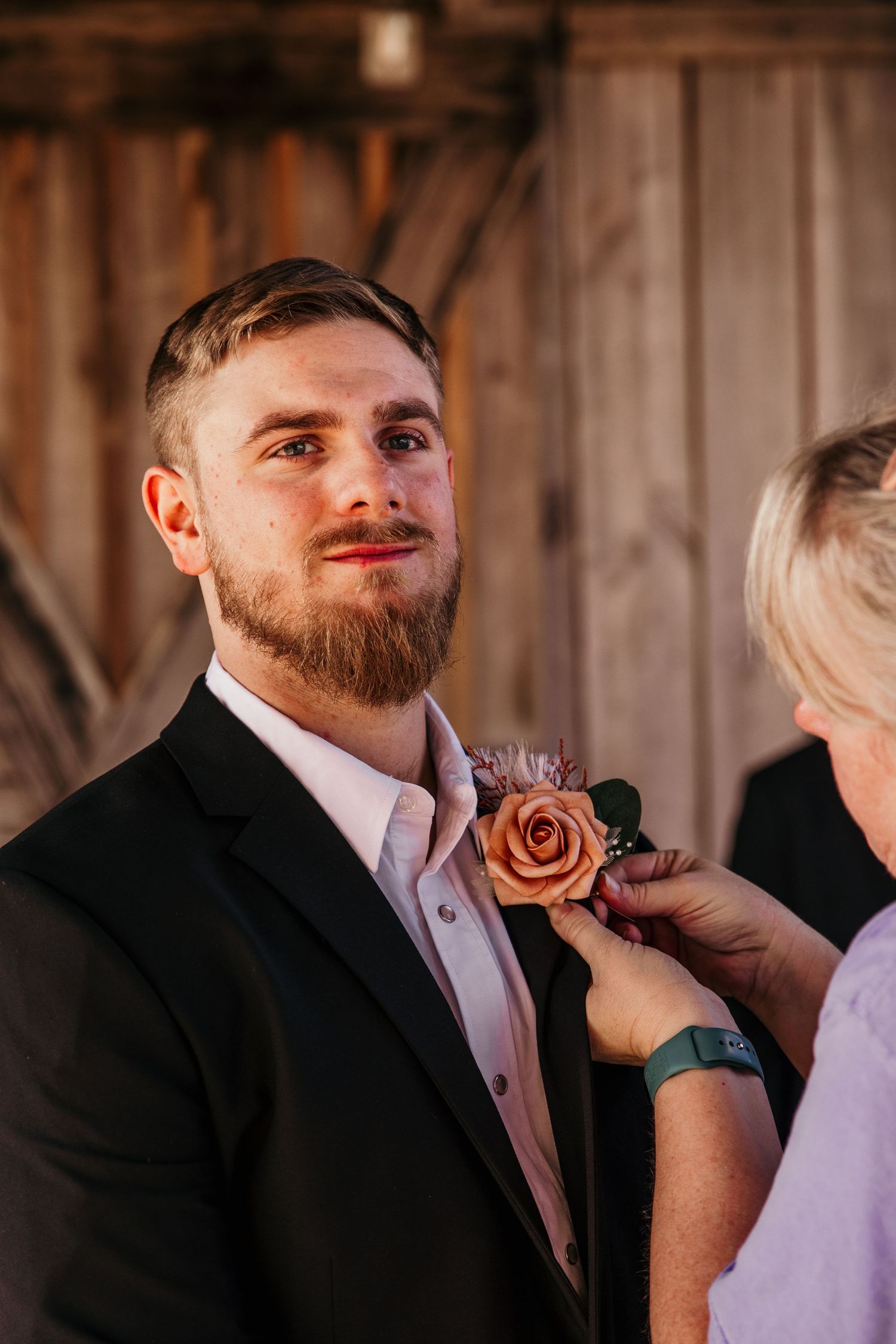 groom portrait while getting boutonniere pinned to jacket