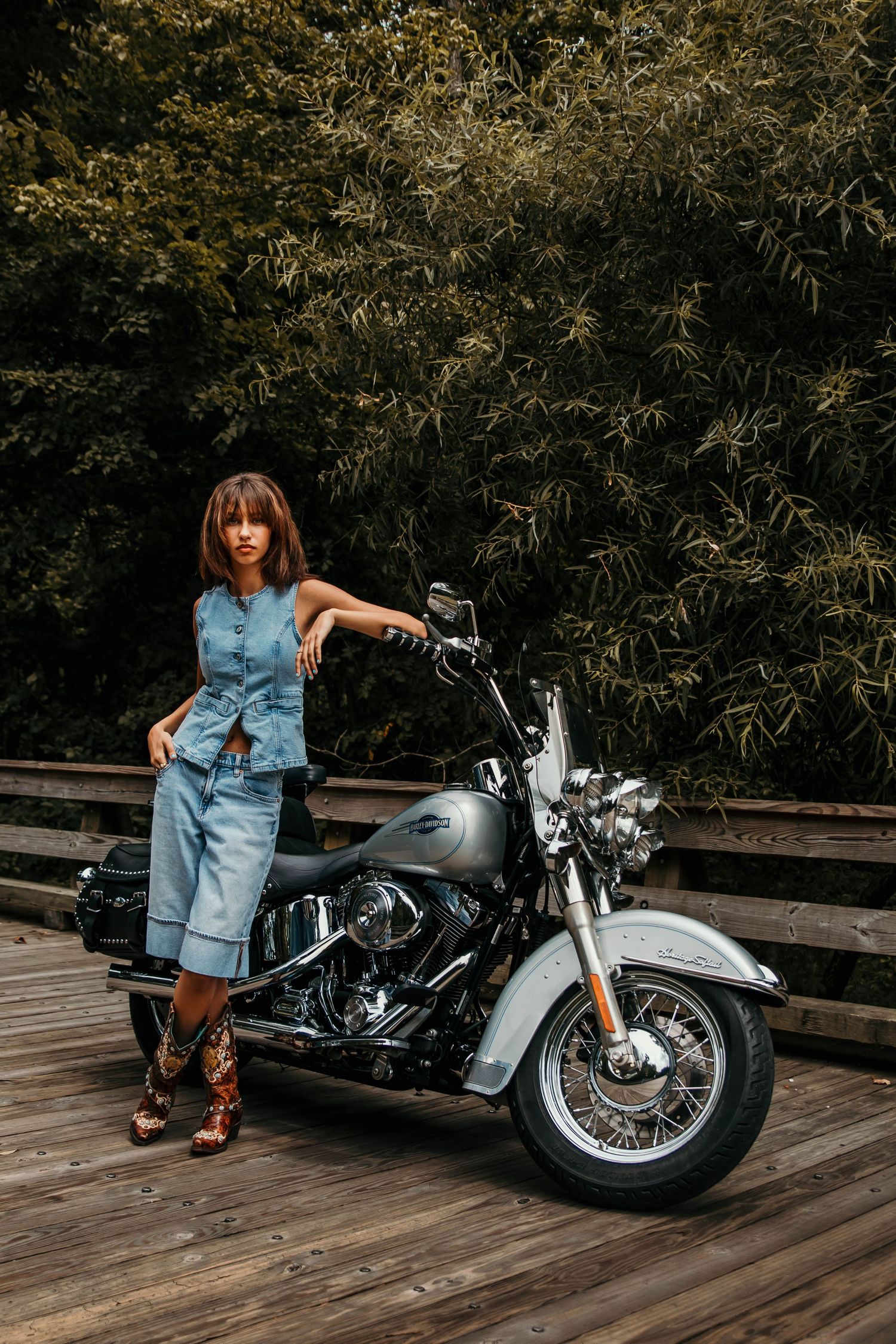Girl leaning on a cool harley davidson motorcycle on old wooden bridge.