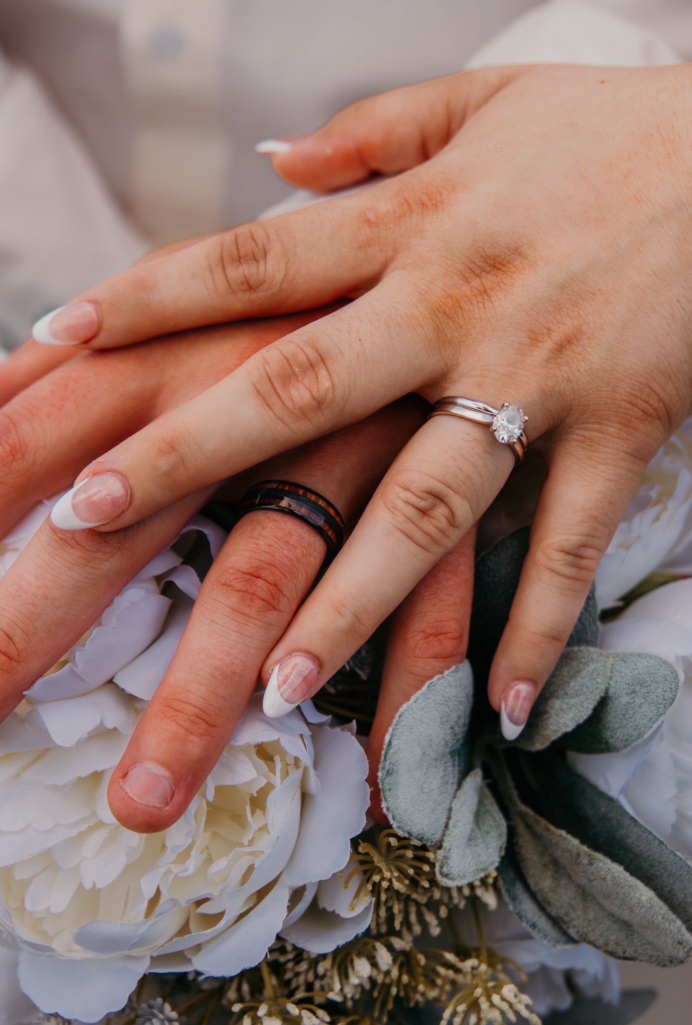 detail shot of bride and grooms hands and wedding rings with bouquet