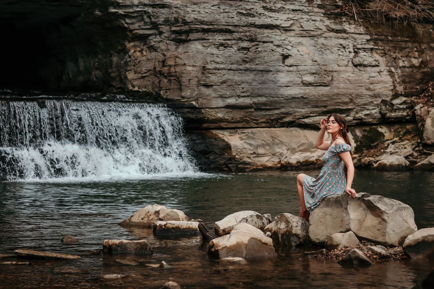 A person sitting in front of a waterfall modeling and showing lots of character.