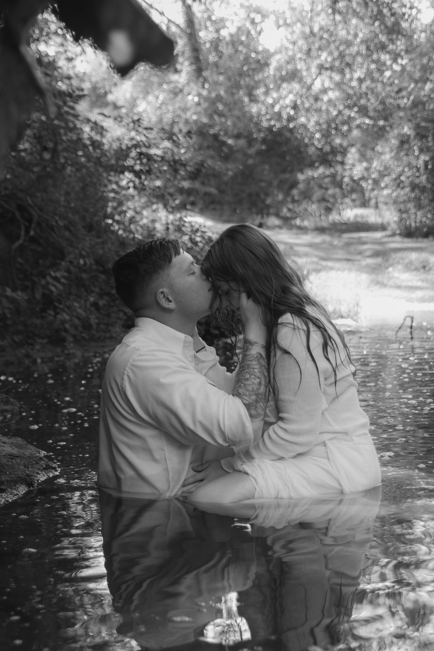 Boy and girl having fun playing in a creek and fully embracing one another.