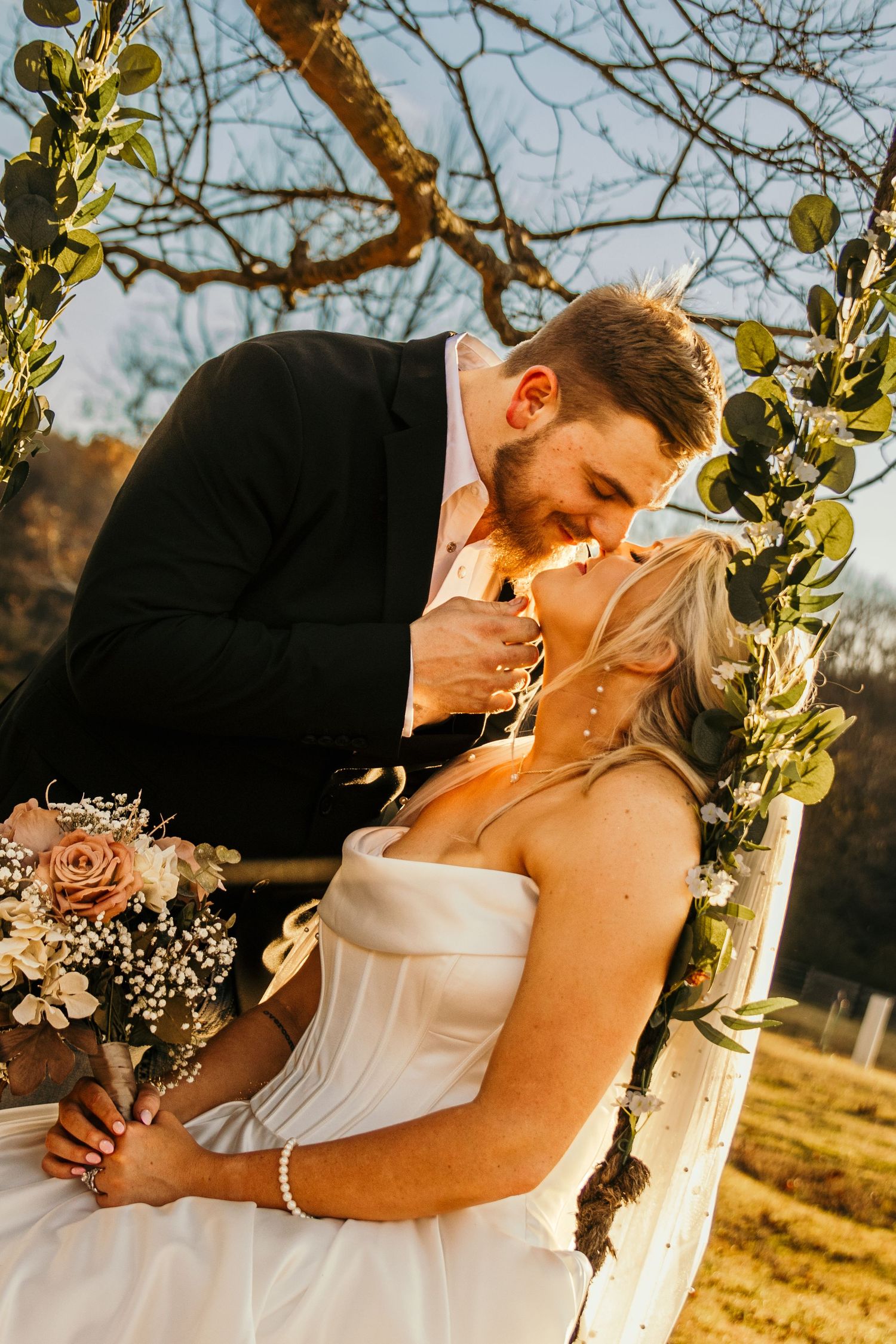bride and groom nose to nose on a tree swing