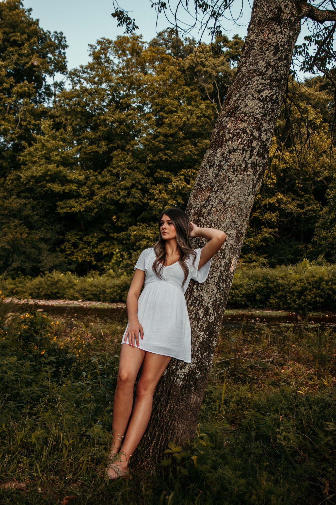 girl leaned against a tree looking into the distance