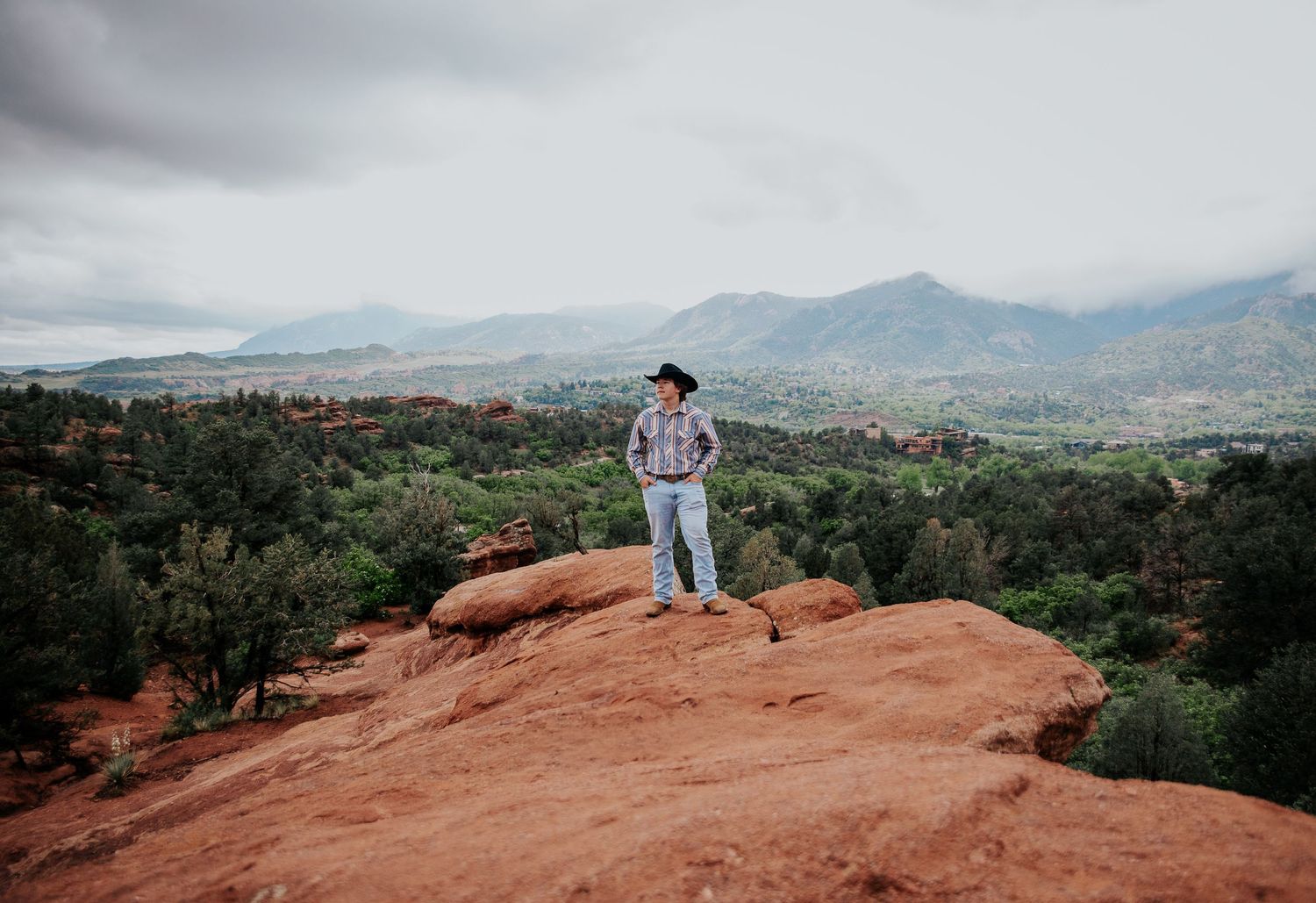 Figure on red rock formation gazing at misty mountain vista at Garden of the Gods in Colorado Springs