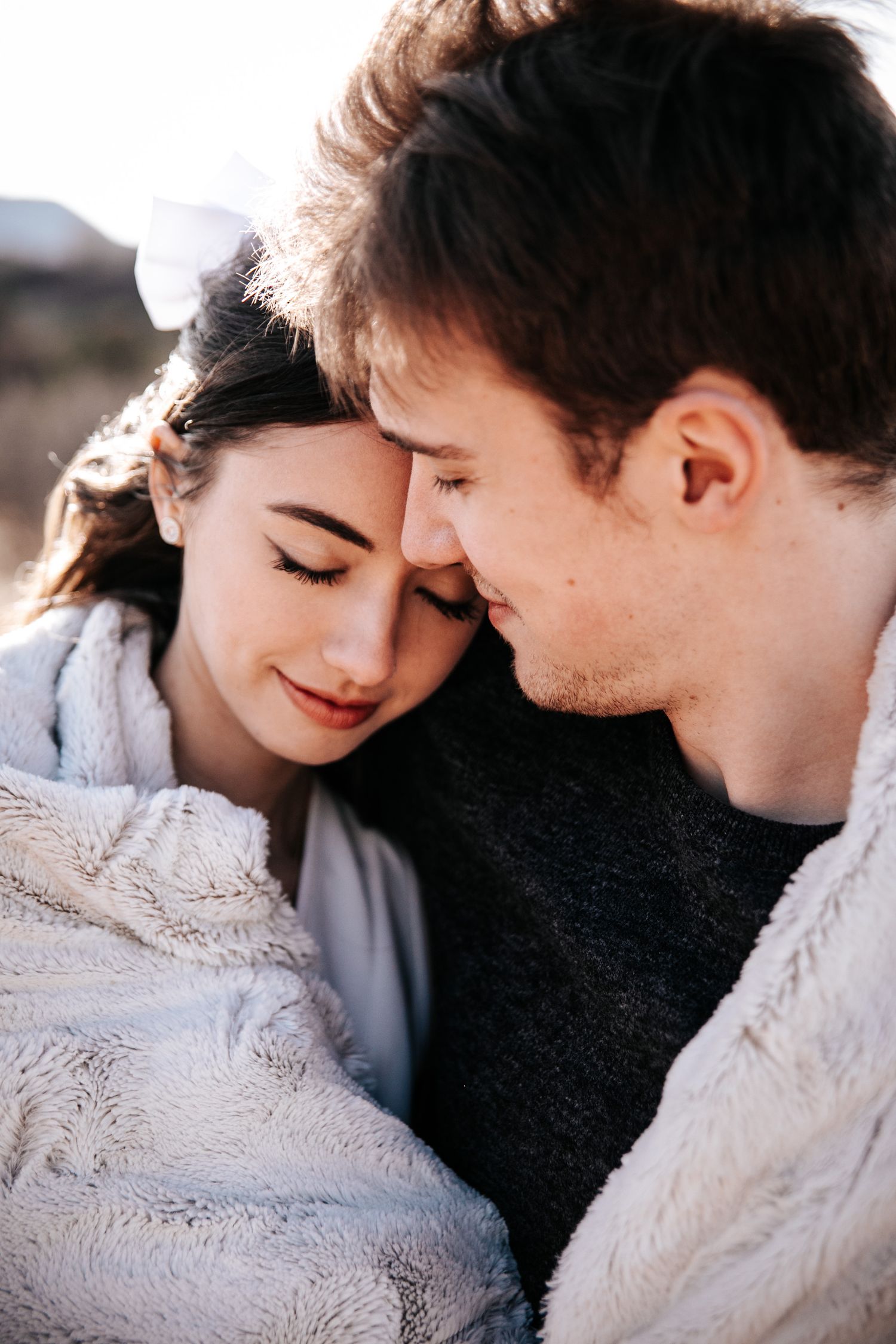 Intimate close-up of a couple snuggling under a cozy blanket outdoors.