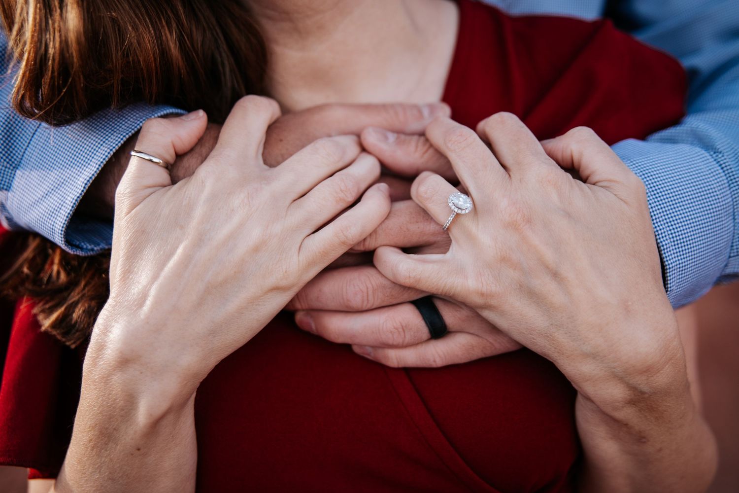 Close-up of hands tenderly embracing against a burgundy sweater.