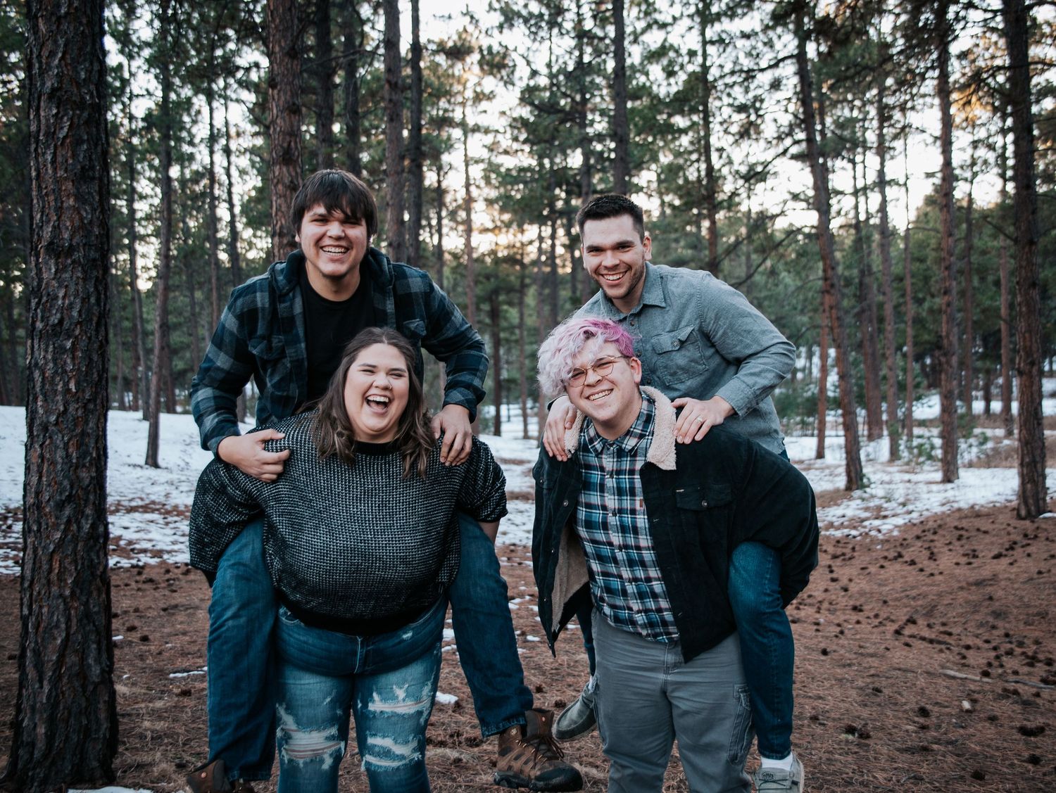 Group of friends having fun and laughing together in a snowy pine forest.