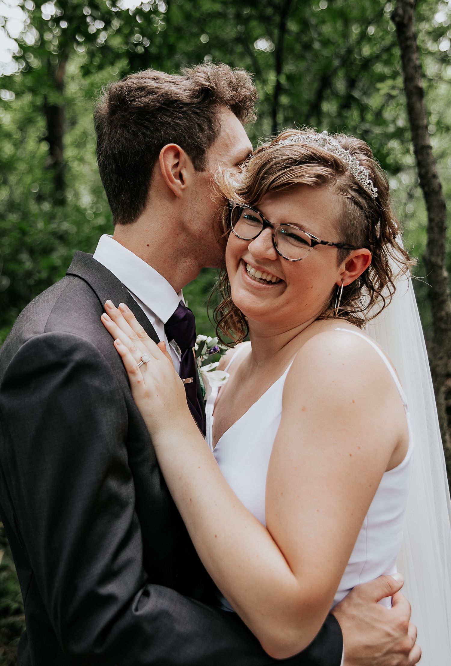 Intimate wedding moment captured between couple in natural woodland setting.