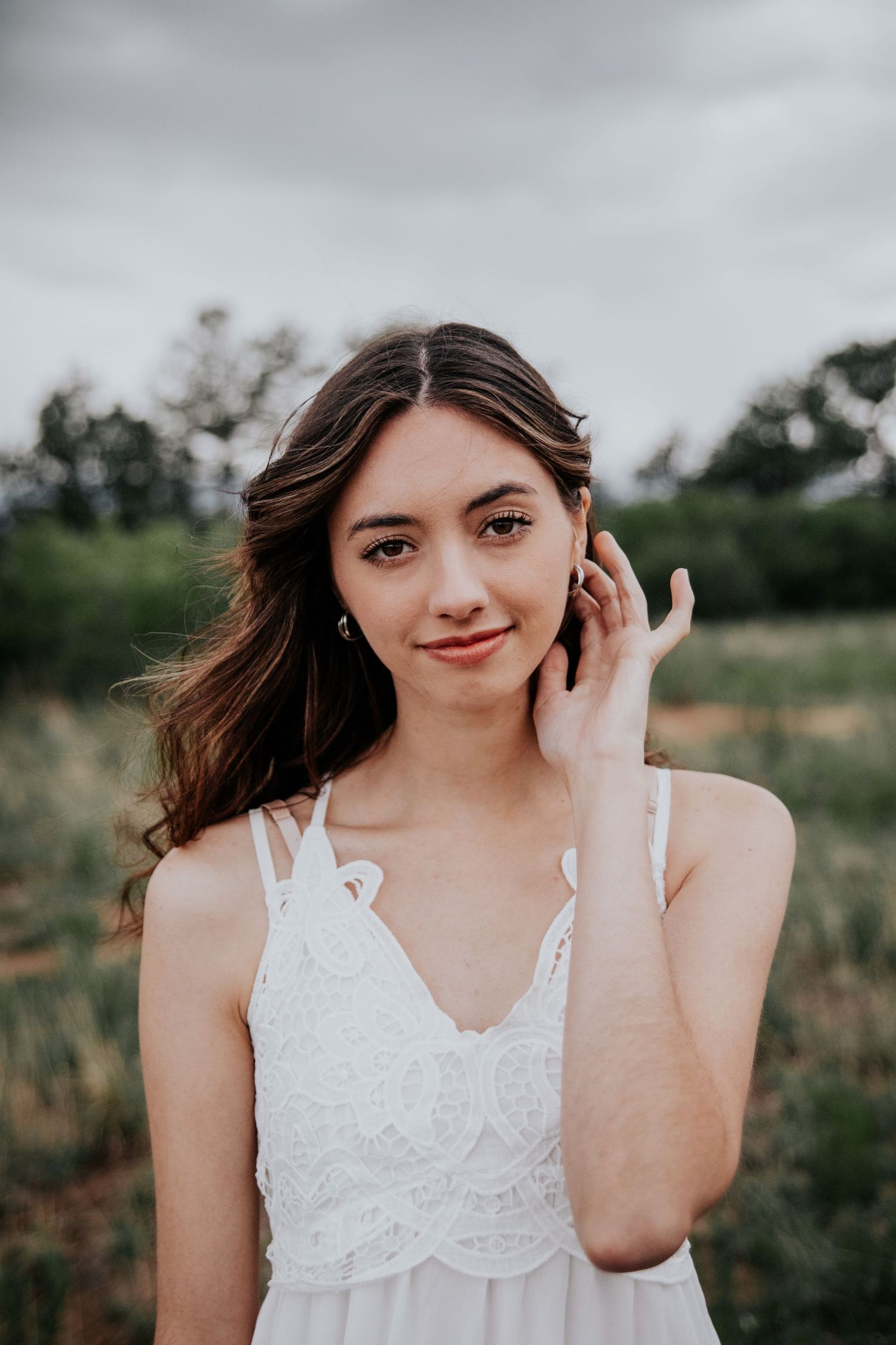 Close-up portrait shots of someone wearing a delicate white lace dress outdoors.