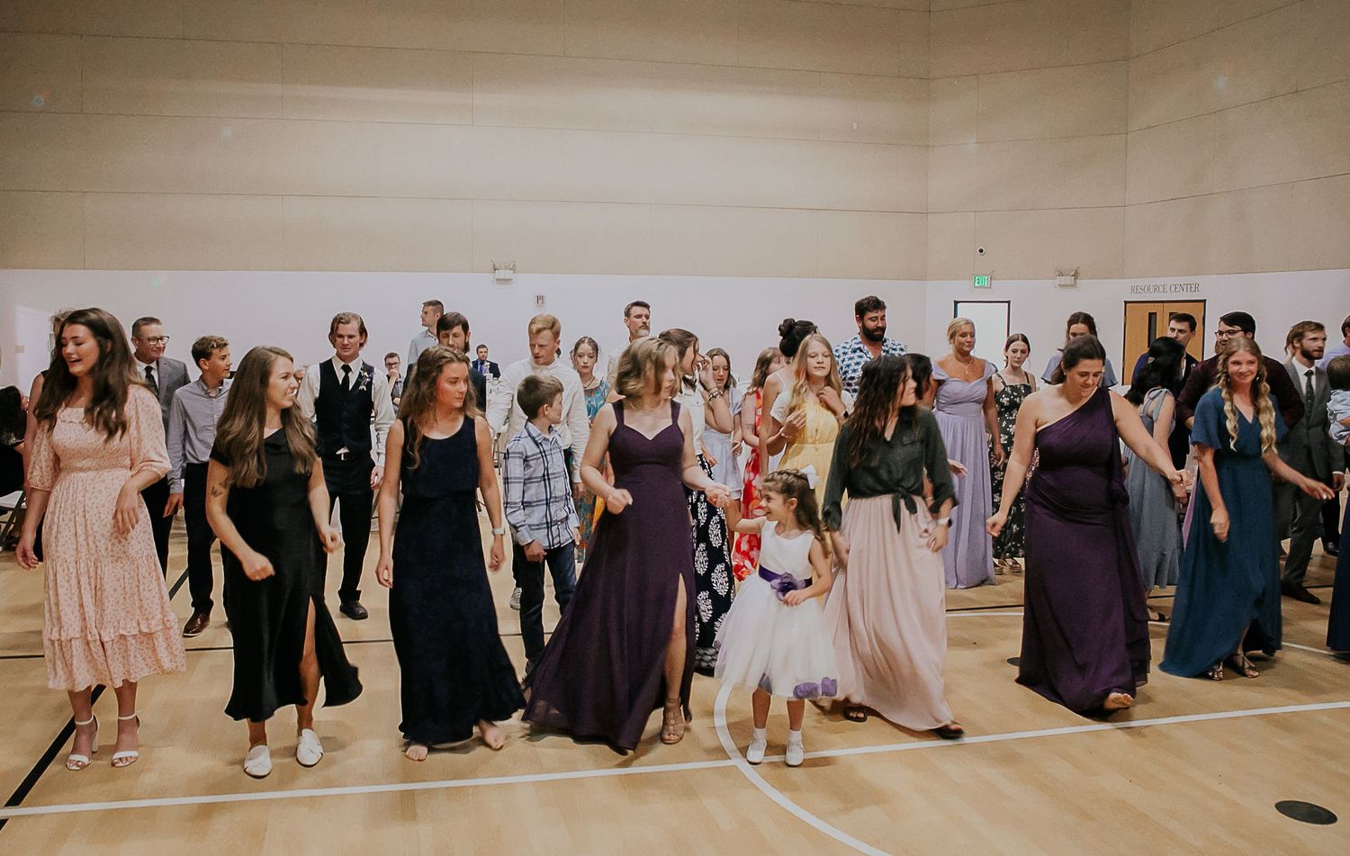 A wide view of guests gathered for a celebration in a spacious community hall.