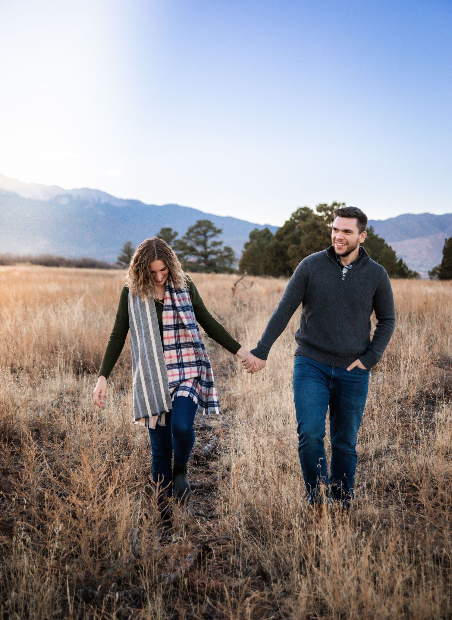 Couple walking hand in hand in Palmer Park with mountains in the background during Colorado Springs engagement photo session