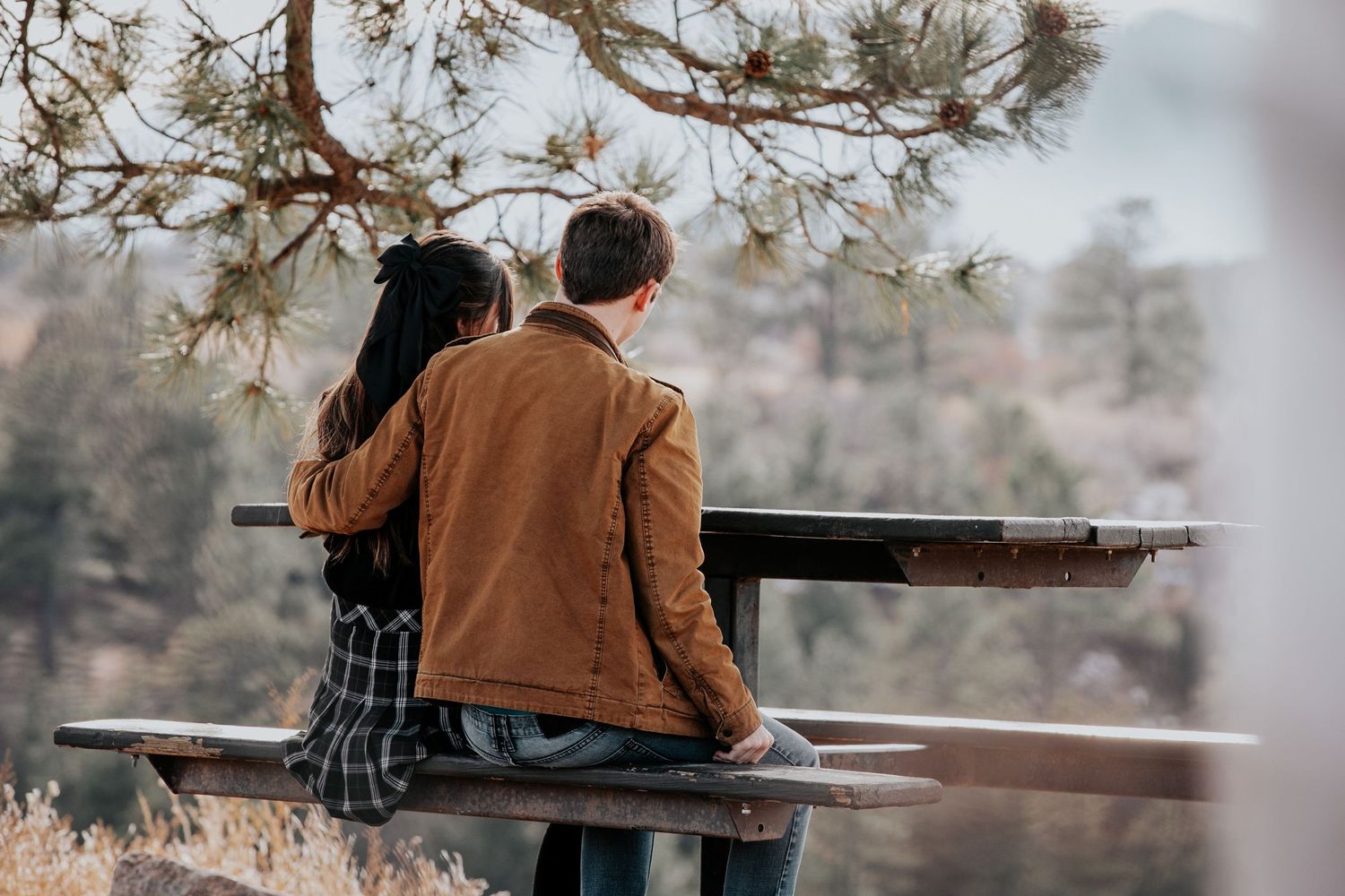 Rustic wooden picnic table with mountain vista backdrop during proposal moment.