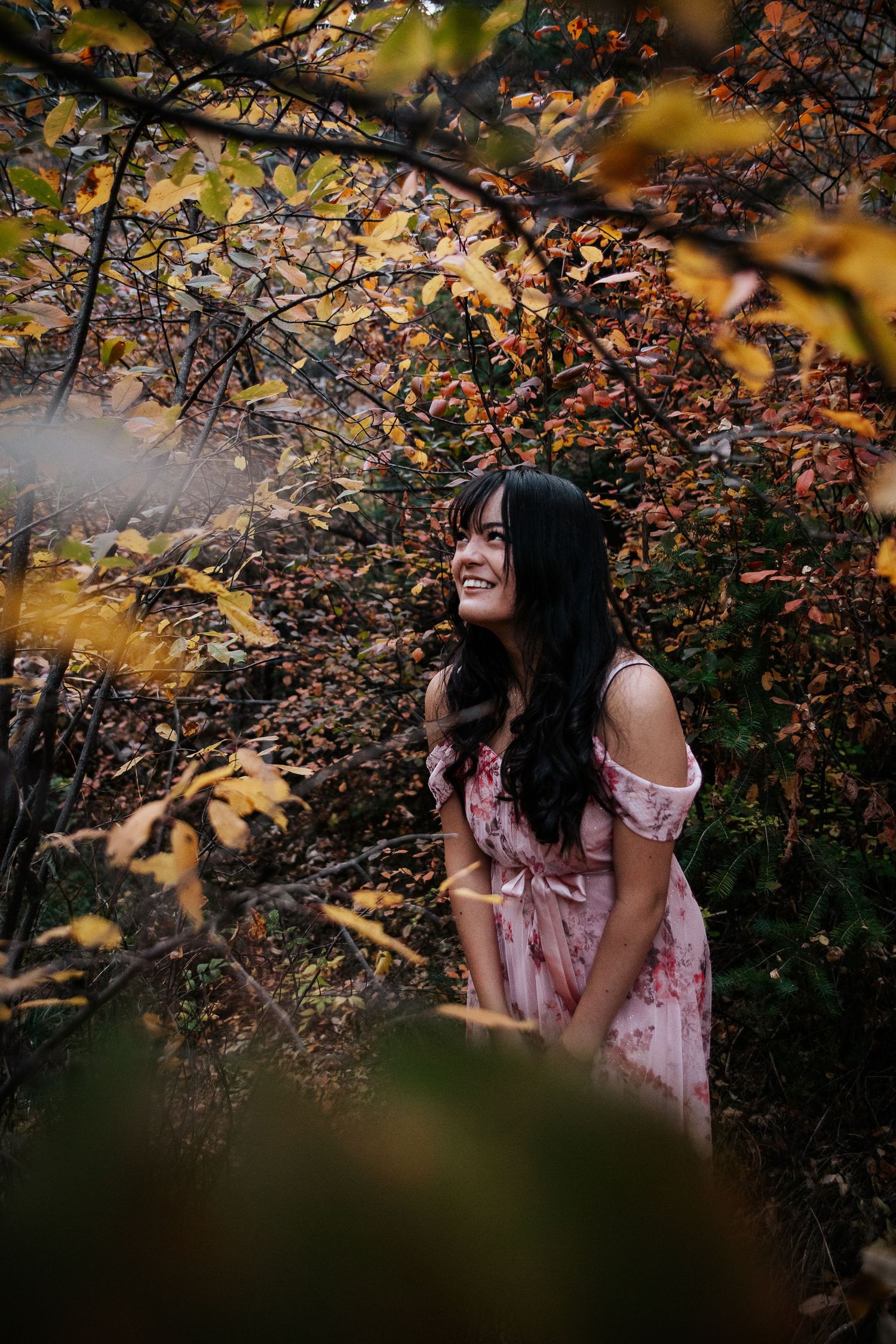 Ethereal autumn photography through golden leaves with a pink floral dress.