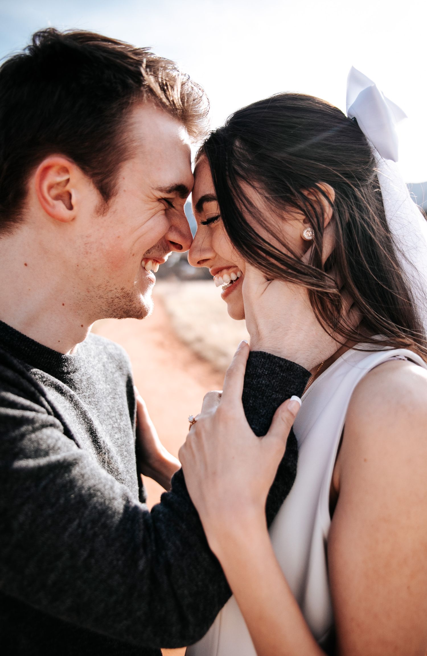 Joyful couple sharing a tender moment and laughing together against a bright background.