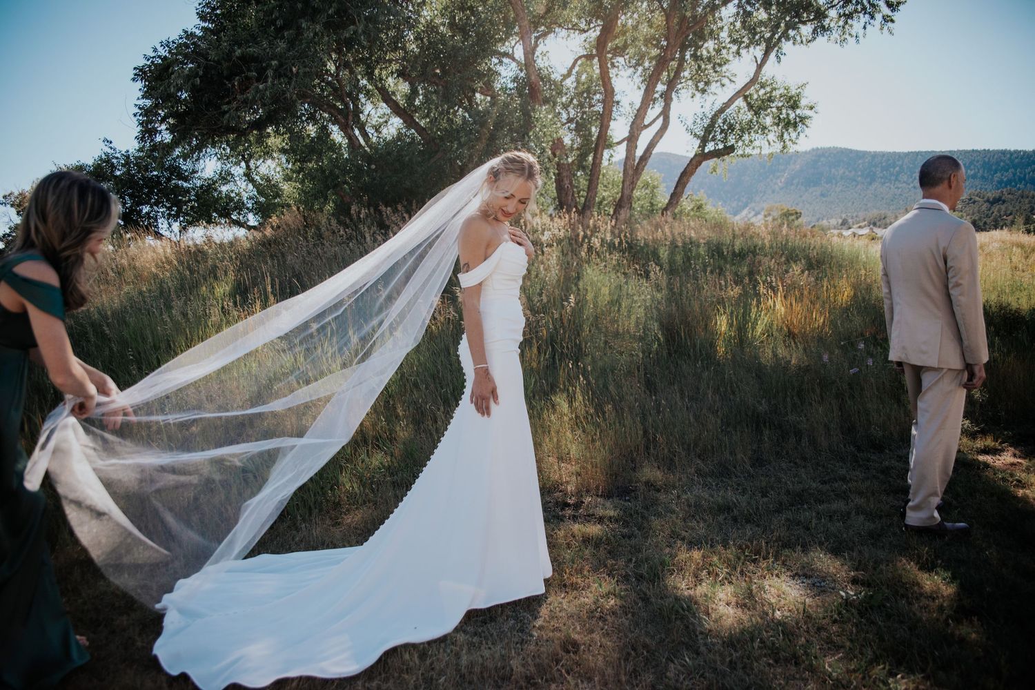 A wedding scene with flowing veil caught in the breeze against a mountain landscape.