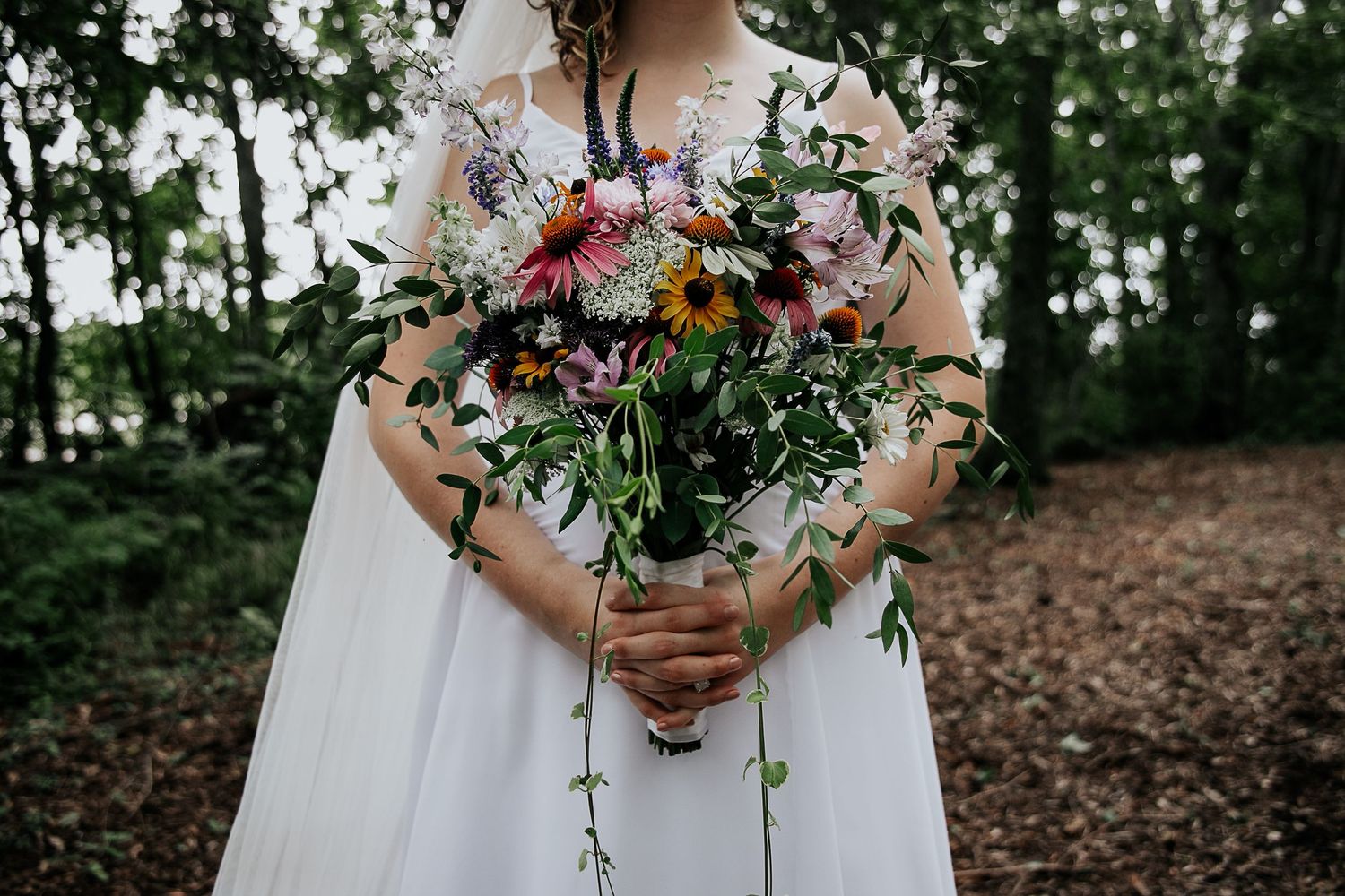 Close-up of a vibrant wildflower wedding bouquet with colorful blooms and cascading greenery.