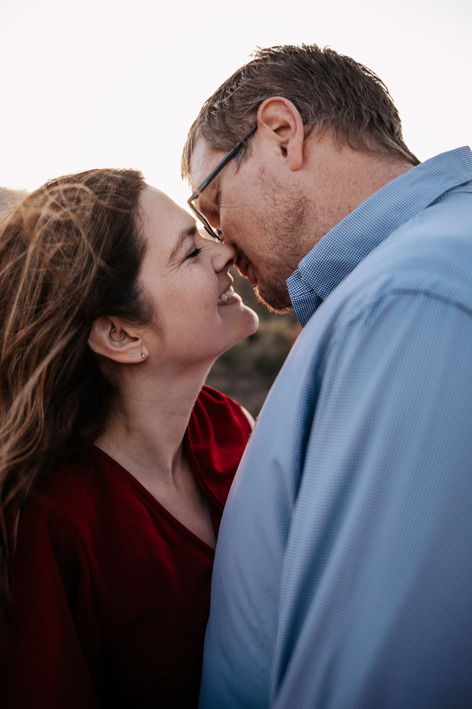 An intimate close-up moment shared between a couple against a bright background.