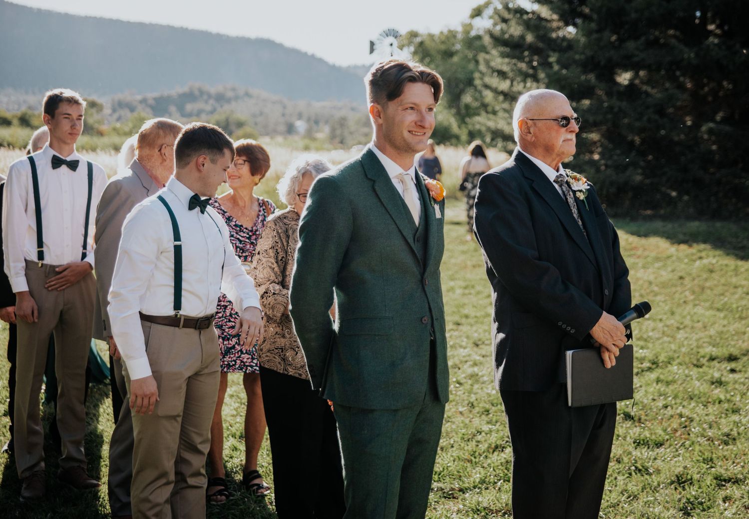 Wedding party members lined up outdoors against a mountain backdrop.