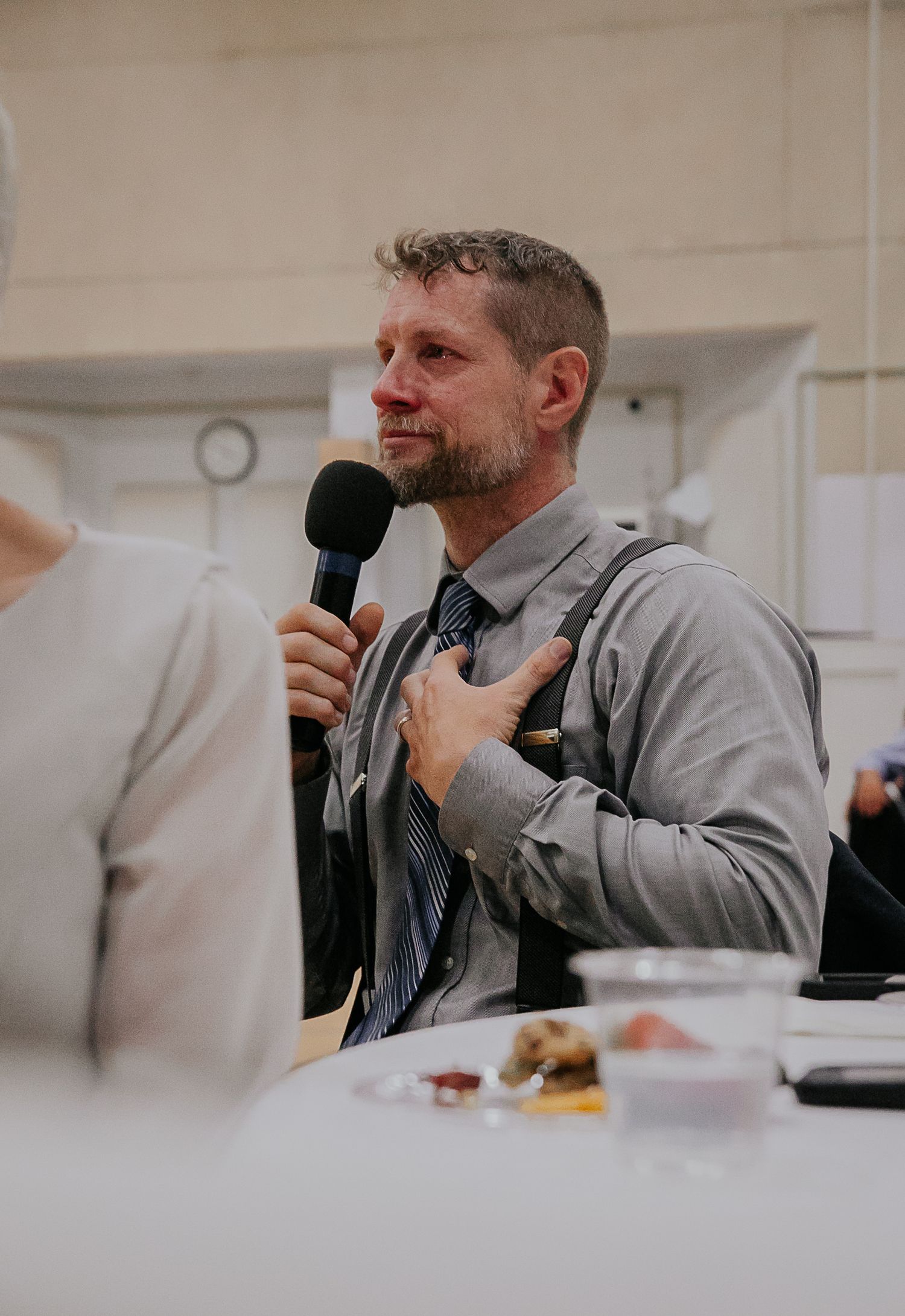 A speaker giving an emotional speech during a wedding reception while holding a microphone.
