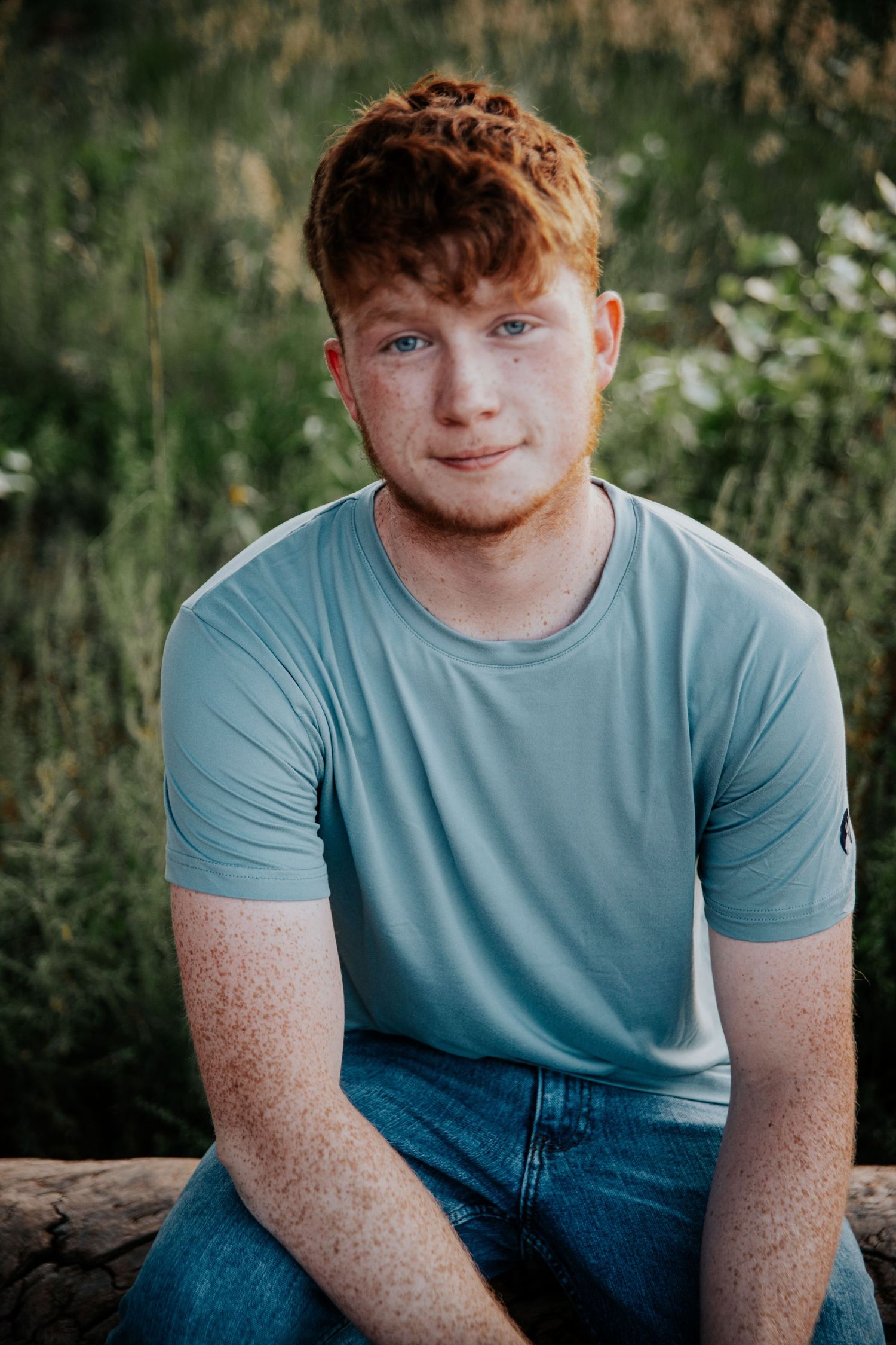 Relaxed outdoor portrait session against a lush green natural background.