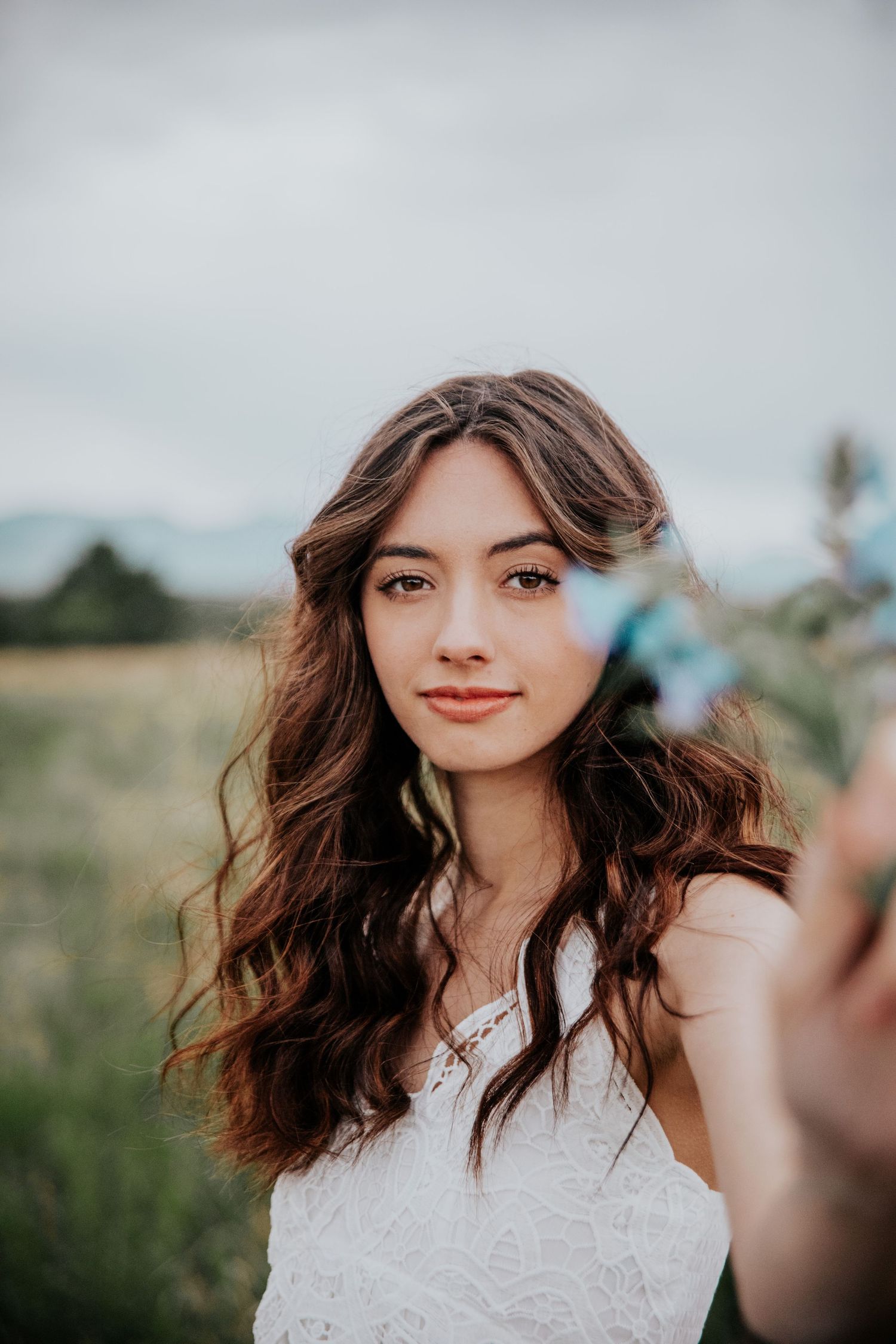 Artistic portrait series showing someone with flowing hair wearing white lace against moody skies.