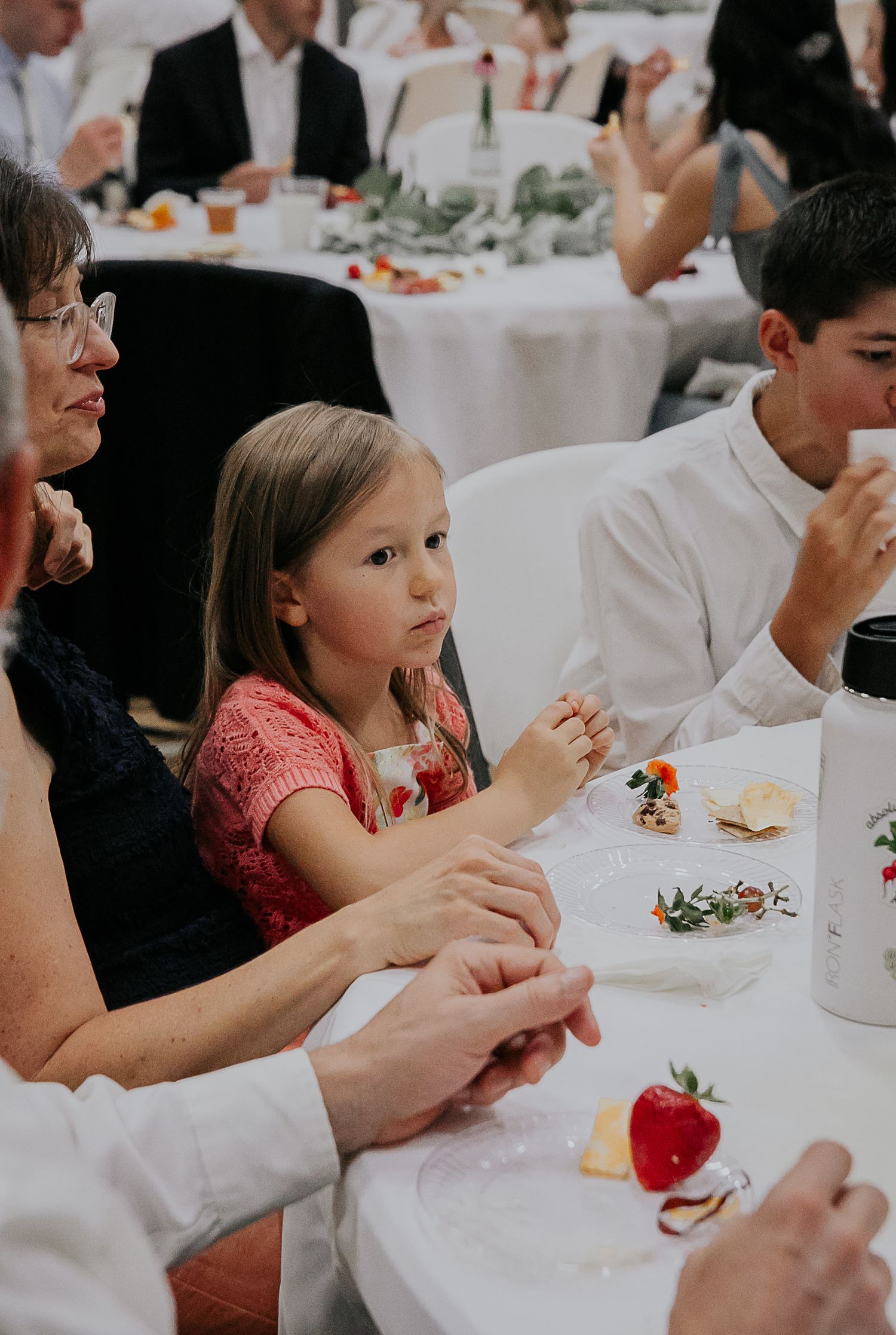 Reception guests seated at round tables with white linens enjoying their wedding meal.